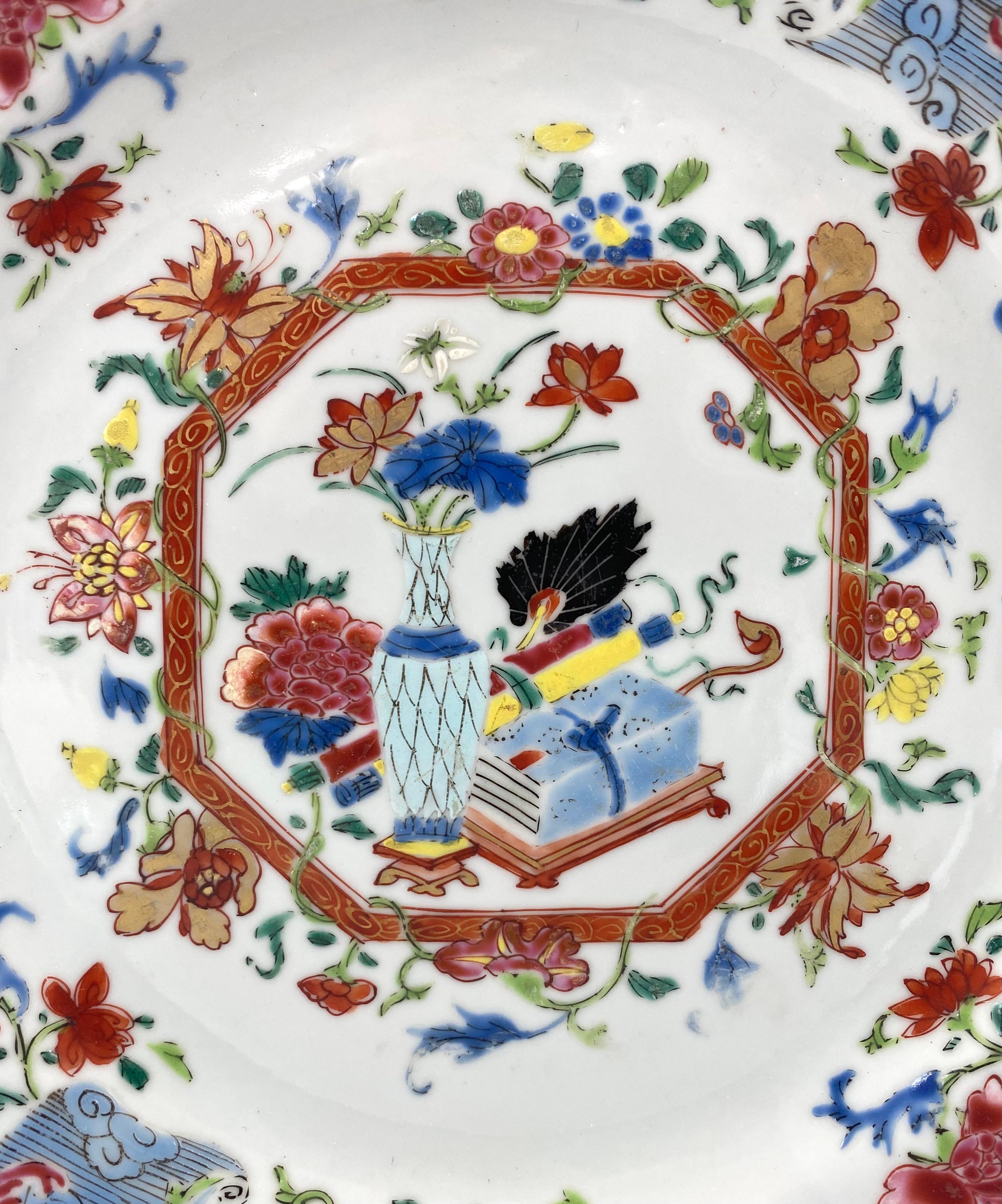 Chinese porcelain, famille rose dish, c. 1740, Qianlong Period. Finely painted in fencai enamels, with an hexagonal panel, containing an arrangement of a vase of flowers on a stand, before scrolls, a sceptre, and a fan, resting upon a further stand.