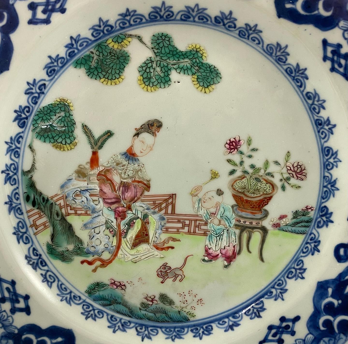 Chinese porcelain plate, c. 1760, Qianlong Period. The shaped plate is carefully hand painted in famille rose enamels, with a scene of a mother and a child, in a garden, with a small dog. By the lady, rests a gilt censer, a box, and a vase of