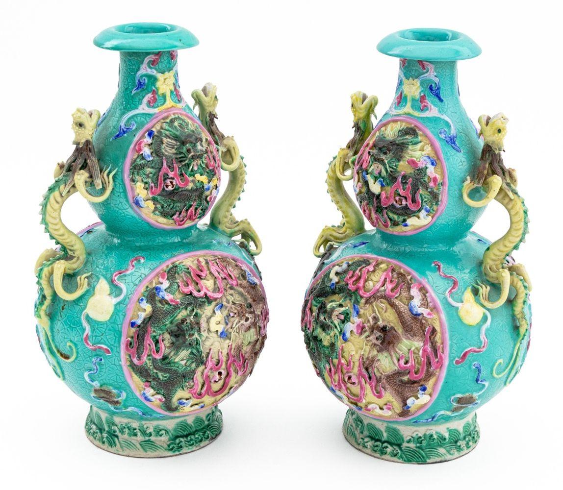 Pair of Chinese Porcelain Double Gourd Vases, 20th century, each with relief dragons with articulated eyes on blue ground and two green dragon form handles, stamped with Qianlong six character seal mark to underside, with carved wood stands.