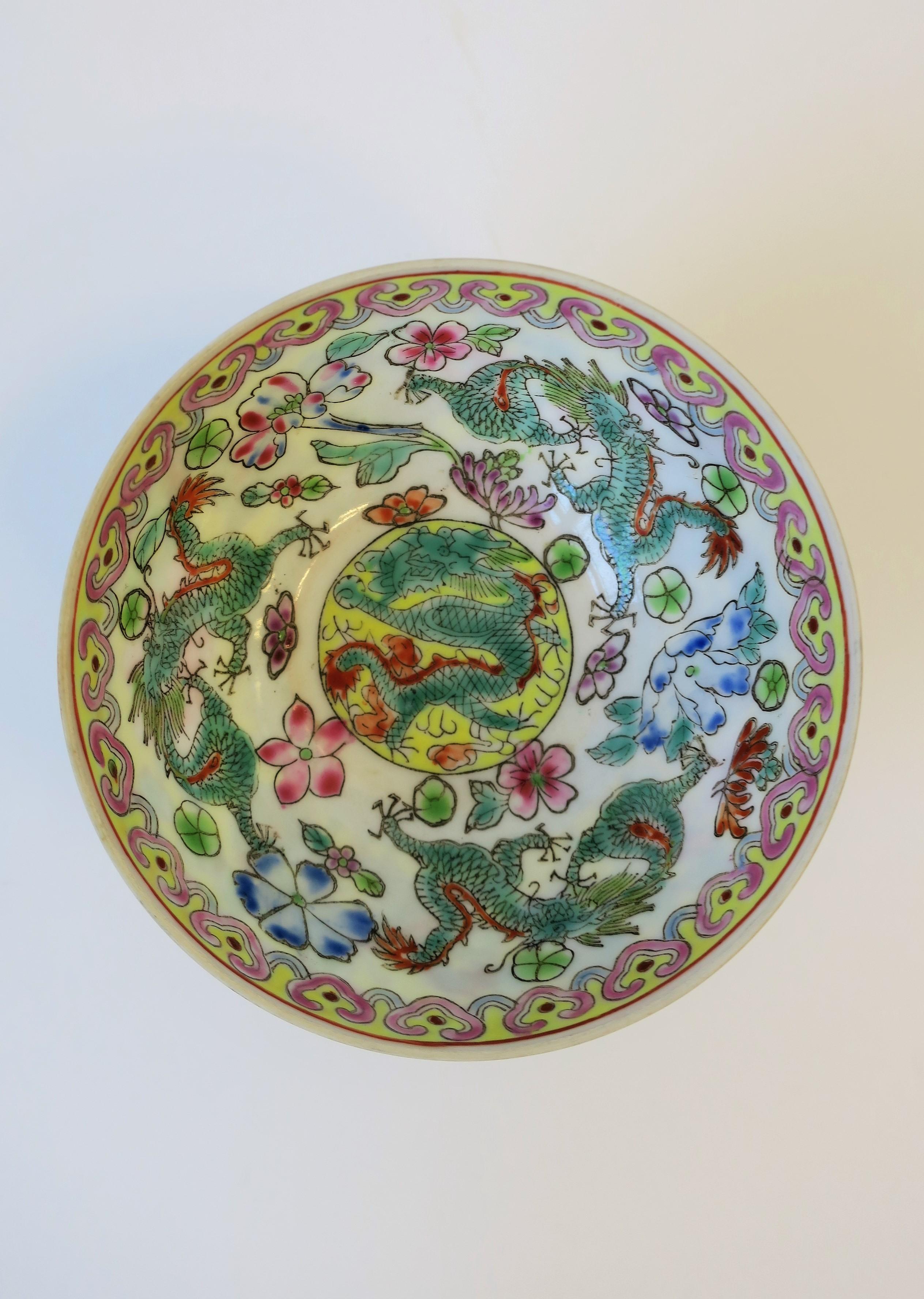 A small, very beautiful, and fine, Chinese porcelain famille Rose hand painted bowl with dragon design, and a carved wood pedestal base, in the style of 18th century version, circa mid-late 20th century, China. Dragons grace the exterior and