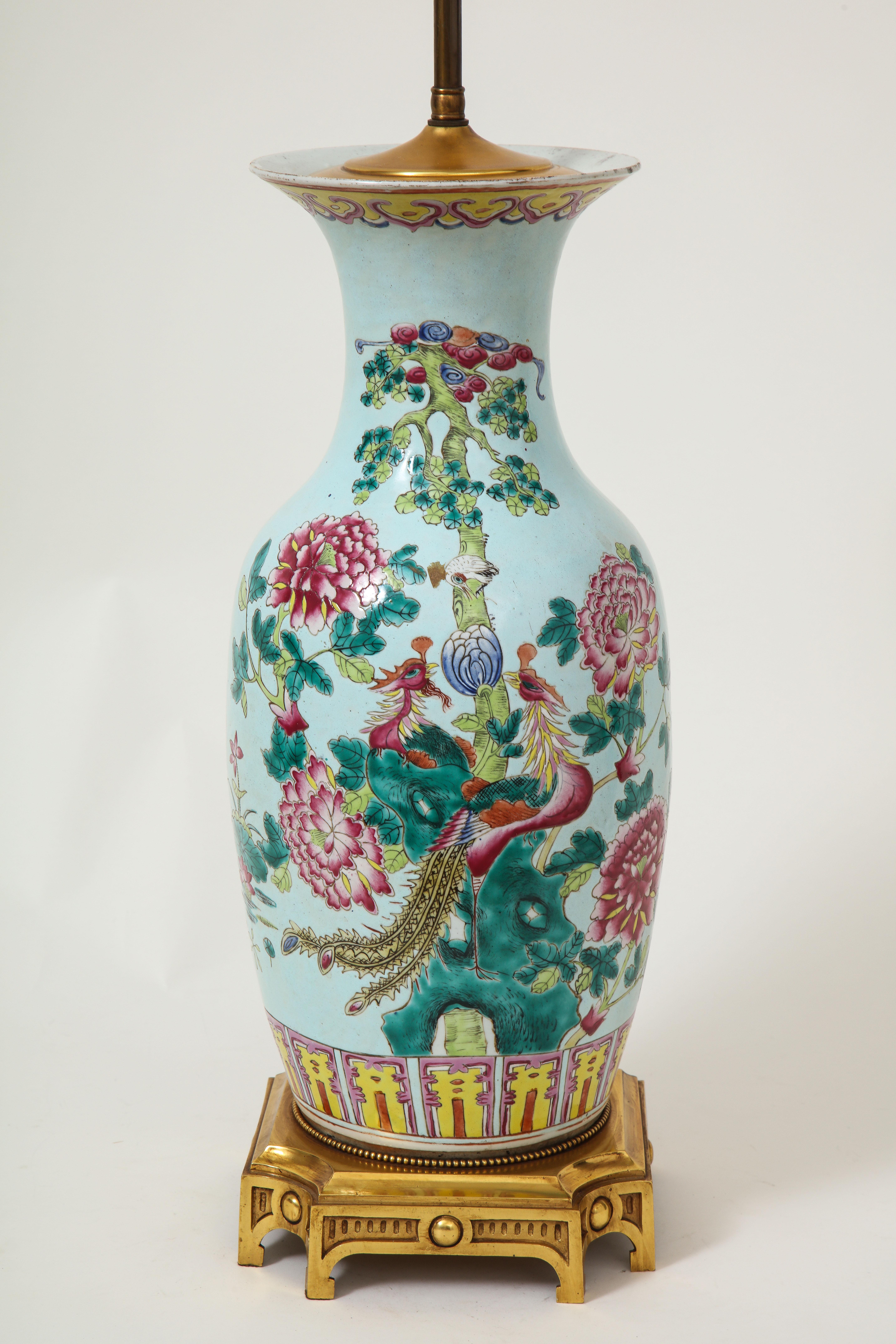 Die Vase in Balusterform ist mit zwei Phönixen verziert, die auf einer blühenden Pfingstrose mit großen rosafarbenen Blütenköpfen sitzen; sie steht auf einem neoklassizistischen vergoldeten Metallsockel und ist mit einem verstellbaren Messingstab