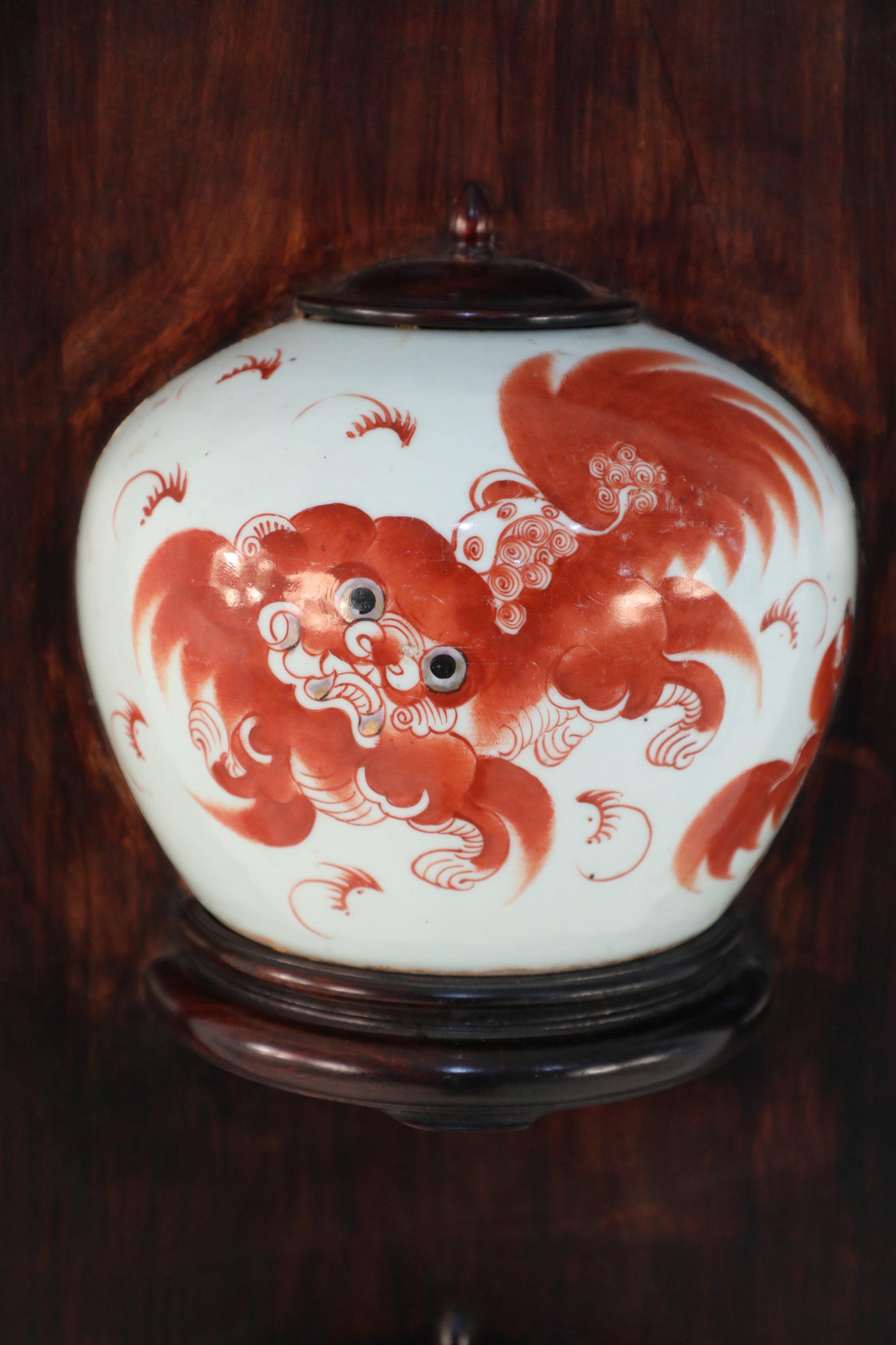 Antique Chinese (Late 19th Century) wall plaque framing a bisected porcelain lidded jar painted with orange foo dogs and characters in wood with a decorative faux bamboo edge.