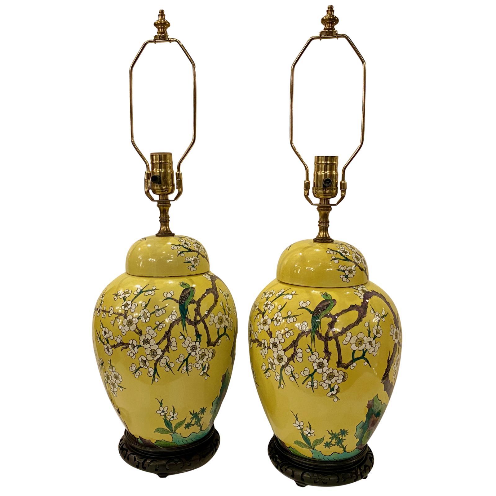 Pair of circa 1920's Chinese hand painted glazed porcelain ginger jar table lamps with flowering tree and bird motif and wood bases.

Measurements:
Height of body 14