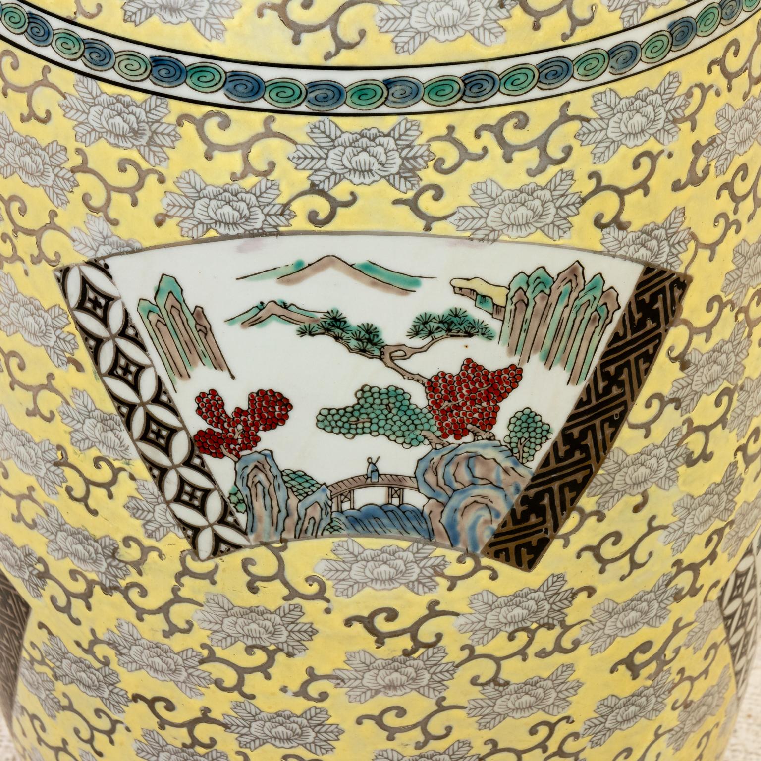 Circa 20th century decorative hand painted Chinese porcelain garden stool or side table with double handles. The piece features a multicolor bird, landscape, and floral motifs on yellow ground. Markings on the base are 