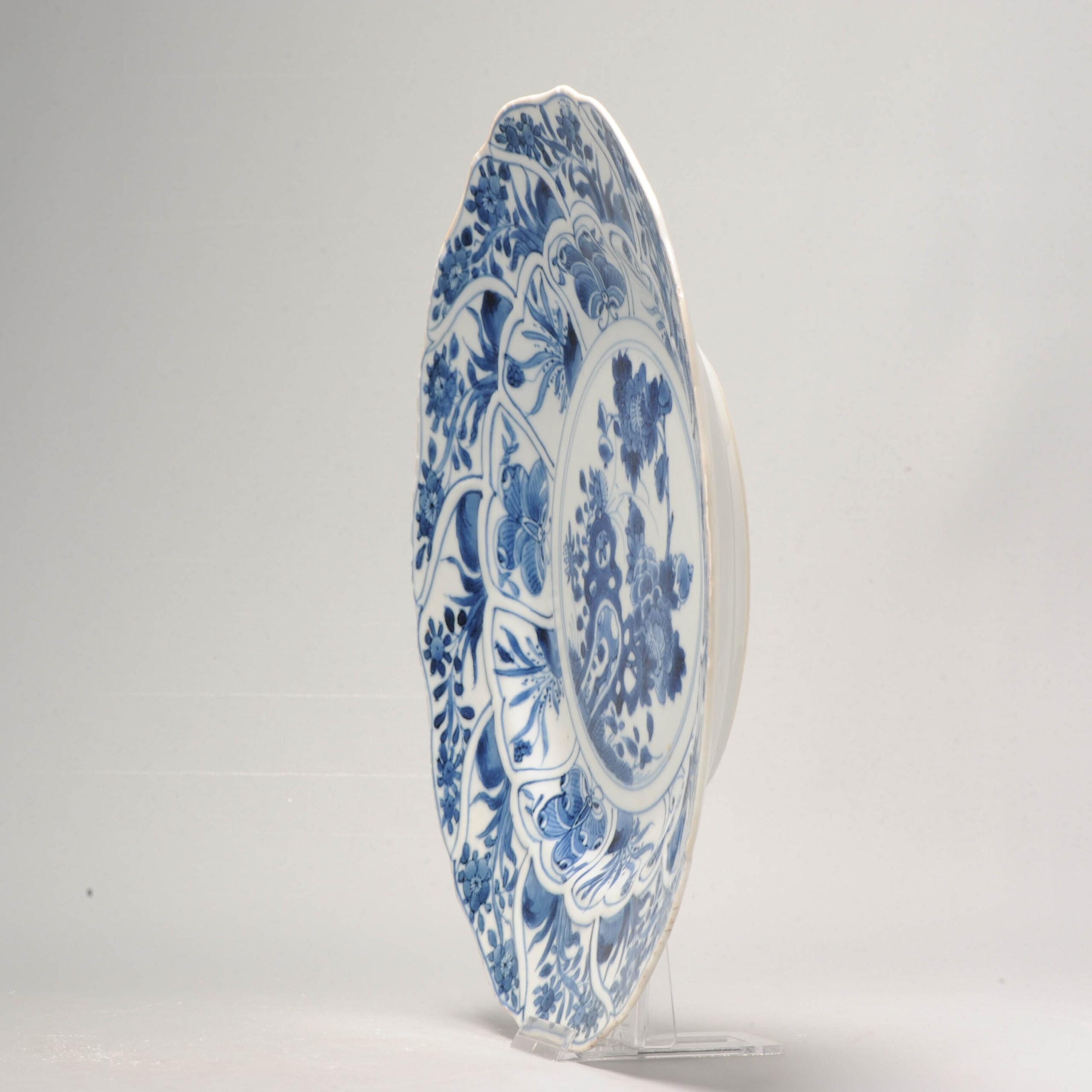 Zum Verkauf steht eine wunderschöne blau-weiße chinesische Schale aus der Kangxi-Periode, die in Form einer Blume geformt ist. Die Schale zeigt eine Szene mit Felsen, Blumen und Schmetterlingen, die kunstvoll in dunklen kobaltblauen Farben gemalt