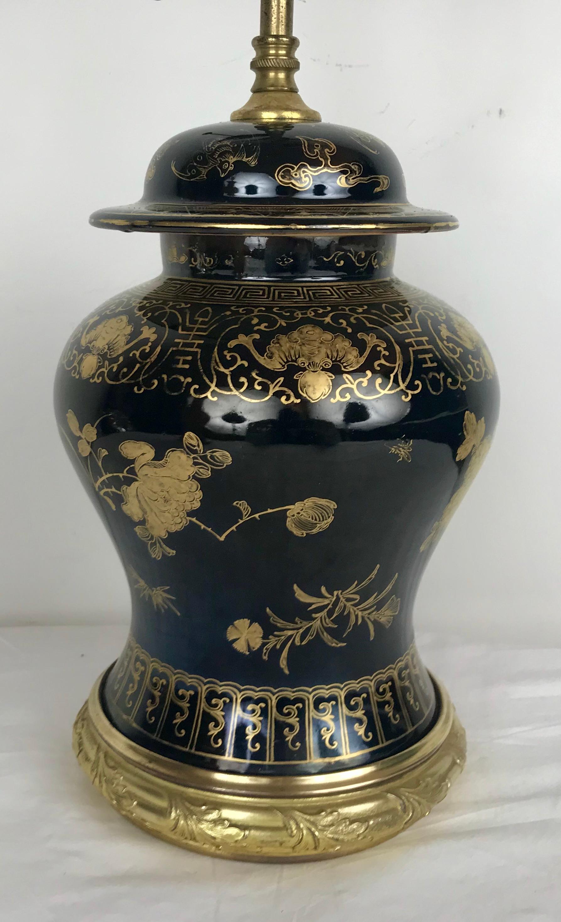 Questa lampada in porcellana a forma di vaso di zenzero con smalto nero a specchio è montata con accessori in metallo dorato. La sua decorazione dorata comprende motivi floreali e insetti.
