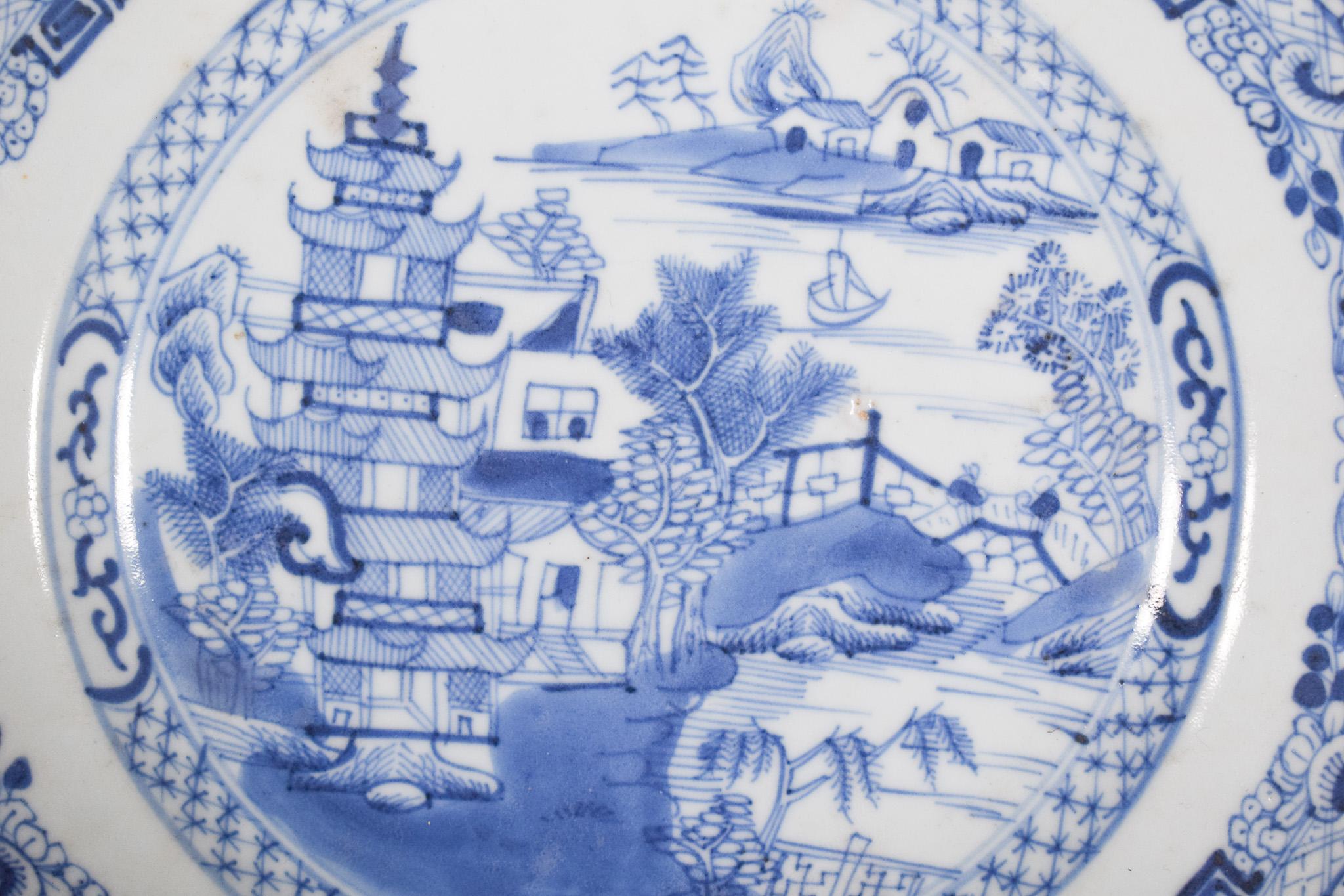 Assiette en porcelaine chinoise pour l'exportation. Décor bleu et blanc, représentant un paysage fluvial, avec motifs végétaux, pont, maison et pagode. Dynastie Qing, période Qianlong (1736-1795).
Riche décor central, avec une rivière coulant entre