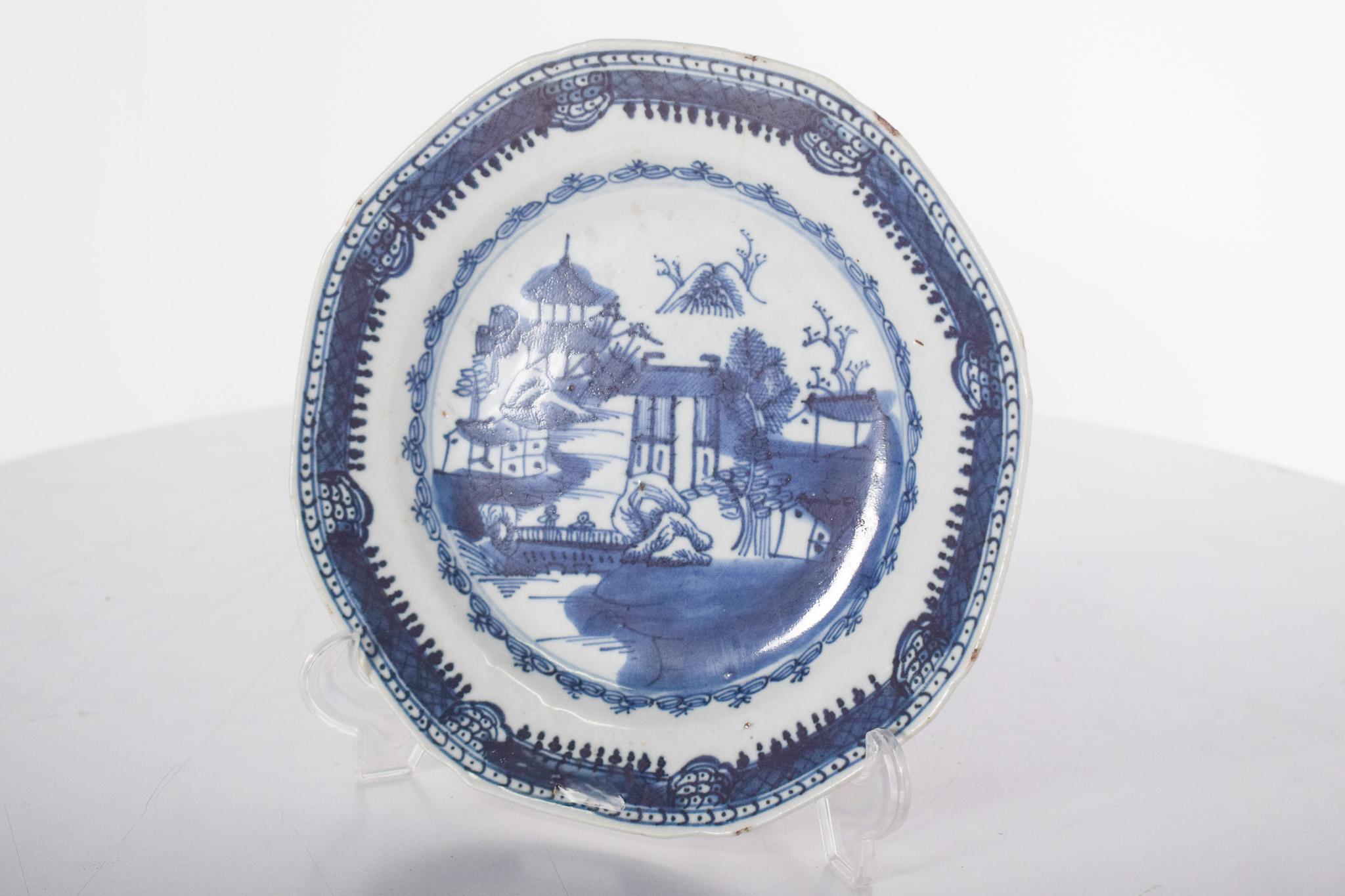 Chinesischer Porzellanteller für den Export. Kantonales Dekor, blau-weiß, Darstellung einer Flusslandschaft mit Bäumen, Pagode und zwei Figuren auf einer Brücke. Qing-Dynastie, Herrschaft Daoguang (1820-1850).
Im Zentrum befindet sich eine