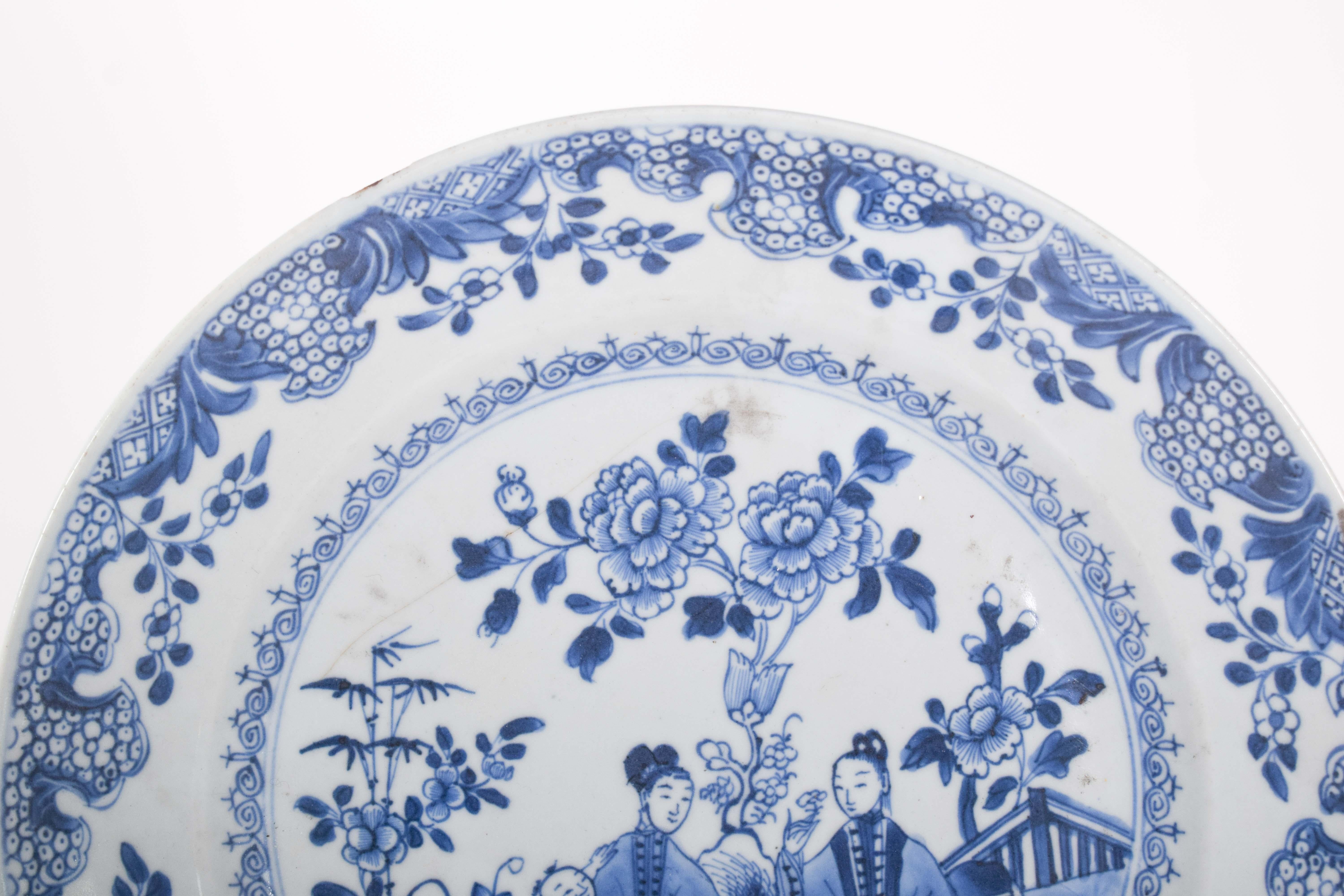 Chinesischer Porzellanteller für den Export. Blaues und weißes Dekor, mit einer Gartenlandschaft mit Blumen und zwei Figuren, eine mit einem Jungen auf dem Schoß. Qing-Dynastie, Herrschaft Jiaqing (1796-1820).
Die in zarten Blau- und Weißtönen