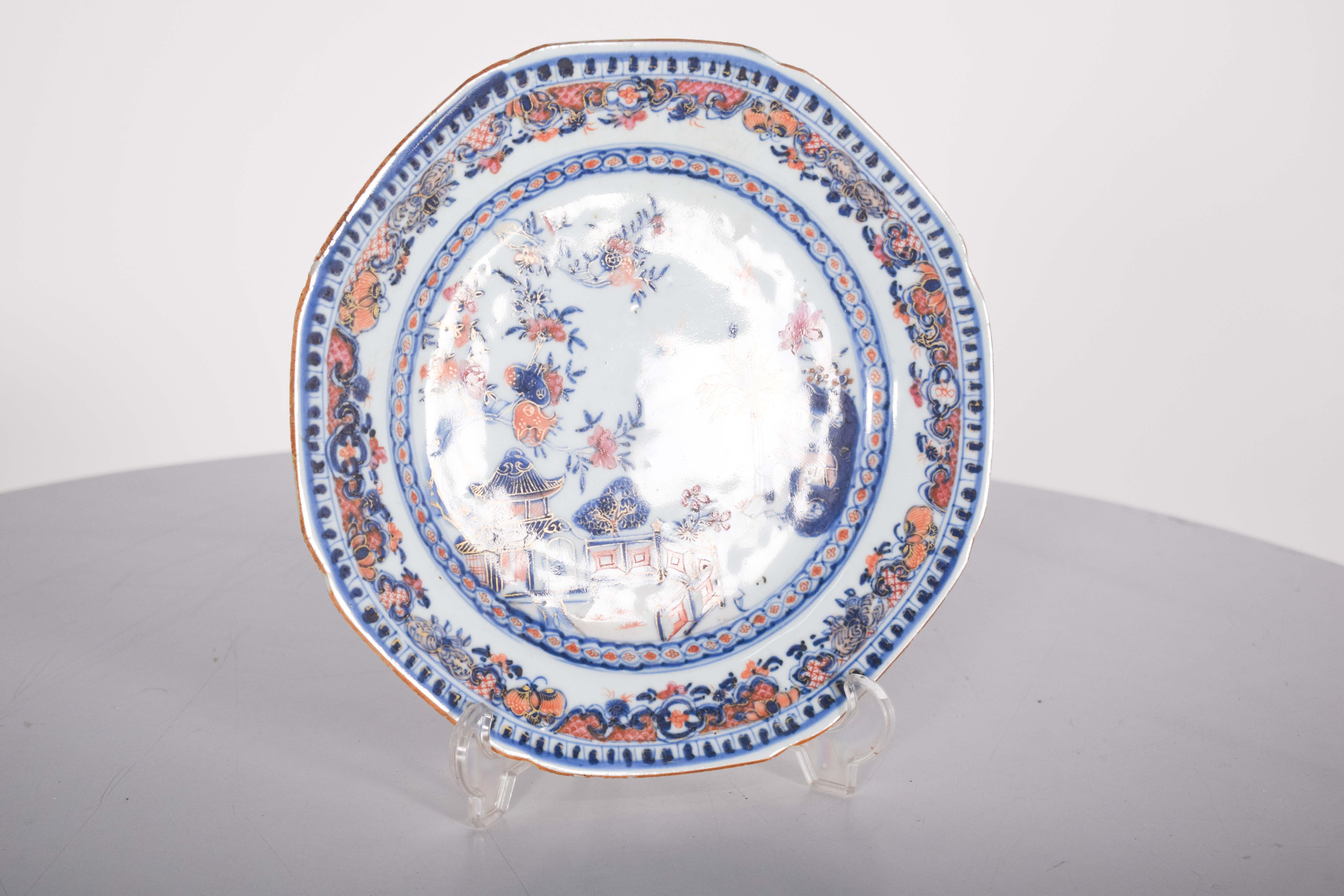 Plato, en porcelana china de exportación, Imari. Decoración policroma en azul, rouge de fer y oro, con un paisaje con pagoda, flores y árboles. Dinastía Qing, periodo Qianlong (1736-1795).
La decoración central representa un paisaje chino