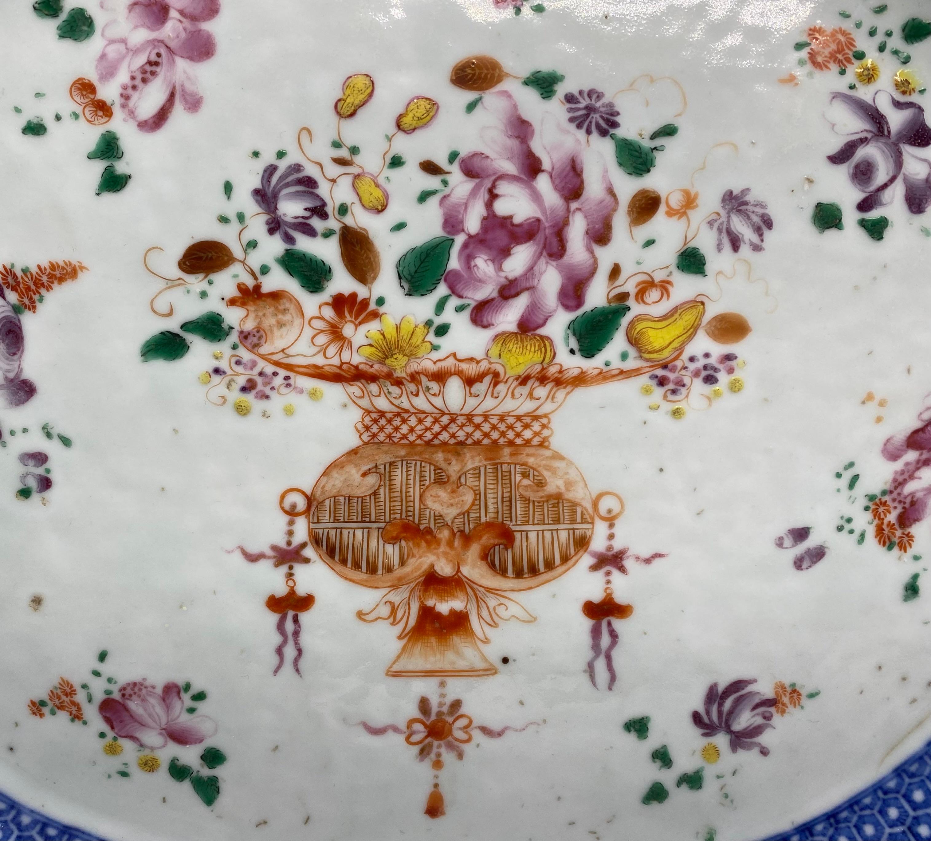 Chinese porcelain serving plate, c. 1760, Qianlong Period. The centre painted in famille rose enamels, with a large elaborate basket of flowers and fruit, surrounded by sprigs of flowers, within an underglaze blue cell diaper motif.
The border
