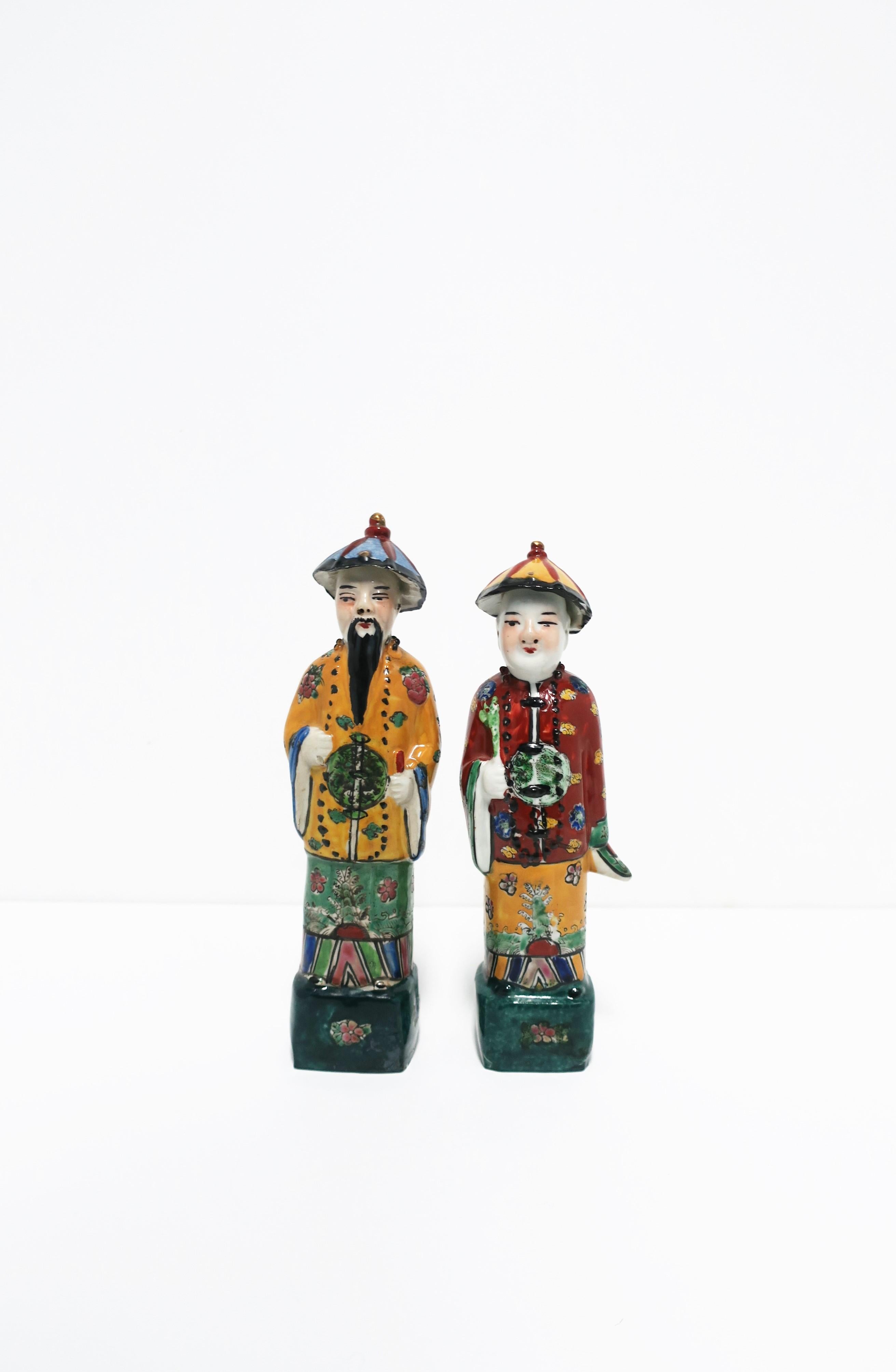 A beautiful set of two (2) Chinese porcelain Qing style male figures, circa 20th century. Painted in rich colors highlighting their robes, hats, and beaded necklaces. Colors include: Green, teal, black, yellow, gold, red, and blue. Stamp marking on