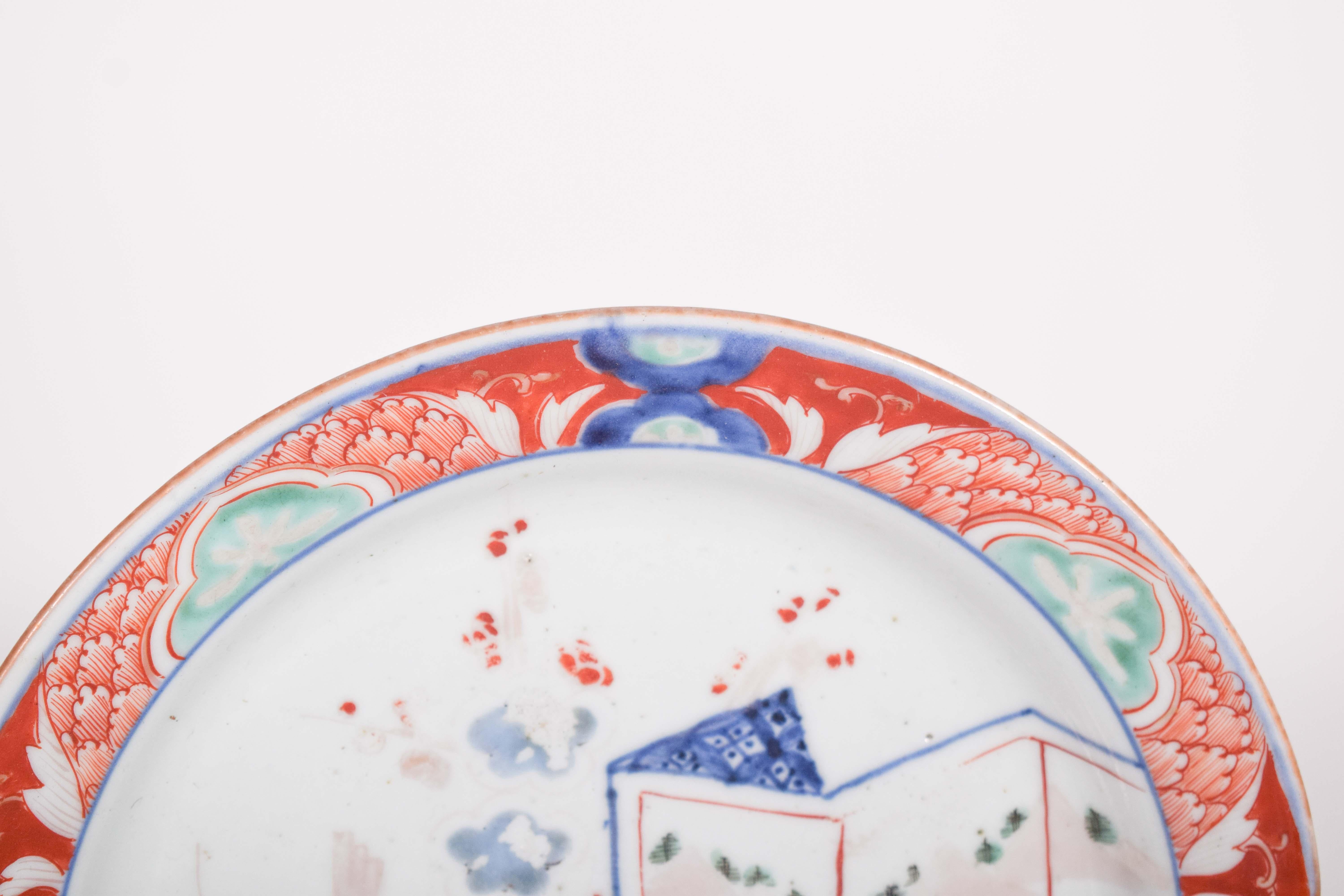 Chinese porcelain soup plate, for export. Polychrome decoration with screen and vase. In the center is a delicate and balanced scene, with an ornate vase in blue and red, decorated with stylized floral patterns. To the side, there is a set of
