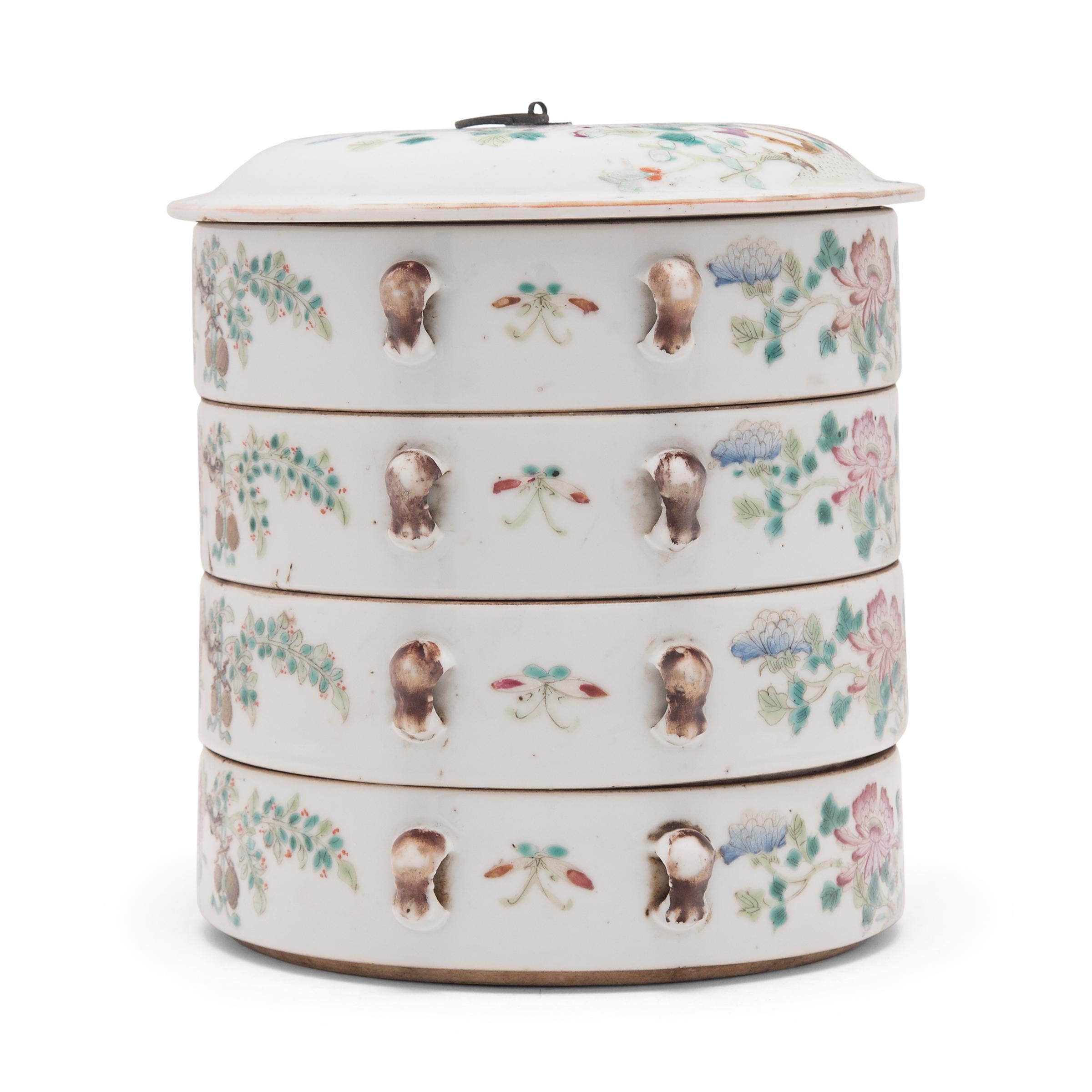 This early 20th-century porcelain stacking box would have been used in a woman's personal chambers to store jewelry and other precious small objects. The large round box has four tiers, each decorated in the famille rose style, with pastel overglaze