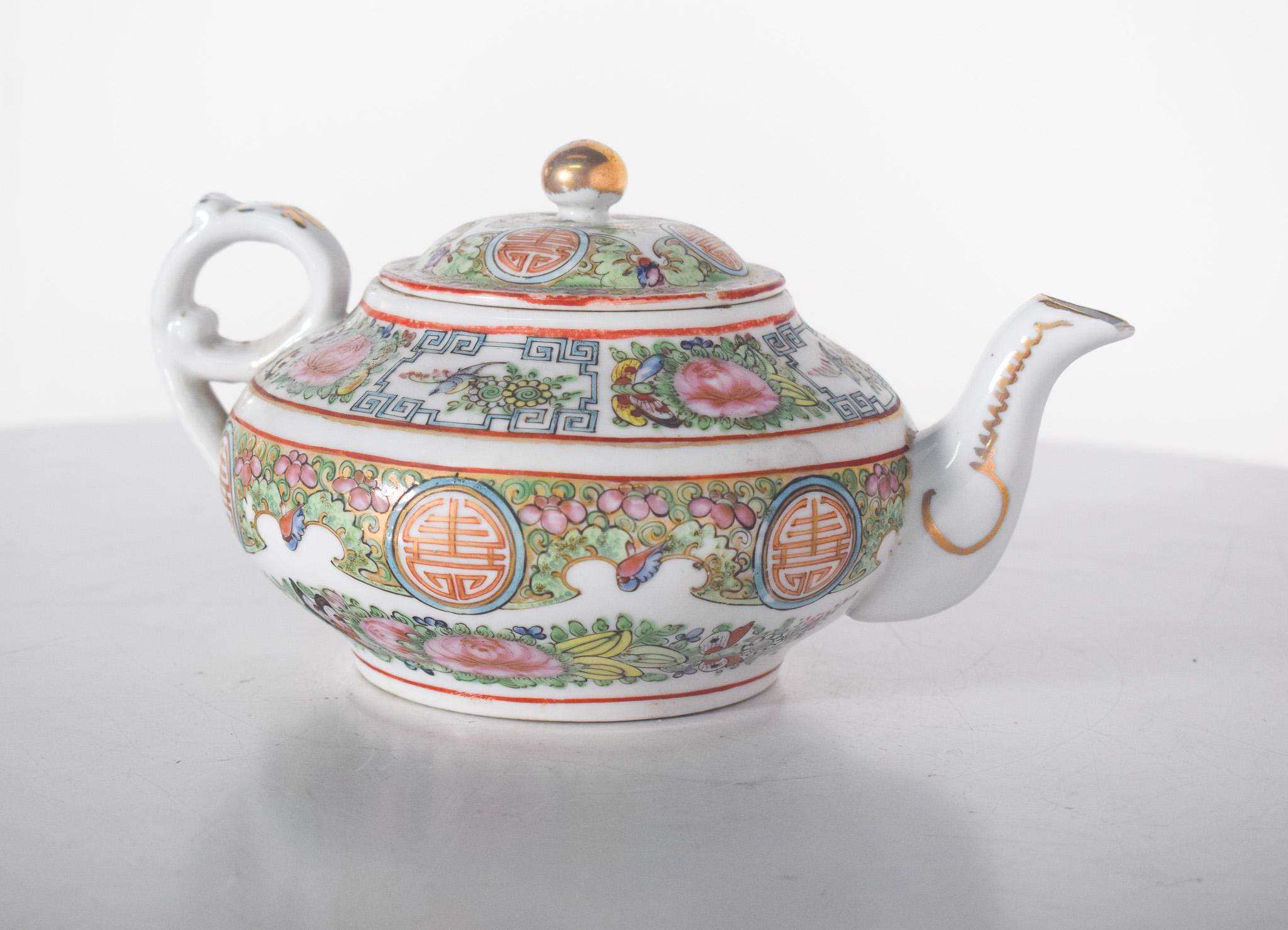 Chinese porcelain teapot. Polychrome decoration with floral motifs, birds and colourful geometric patterns on a white background and painted in vivid shades of green, pink, orange, blue and gold, the sides show Chinese symbols in red inside circular