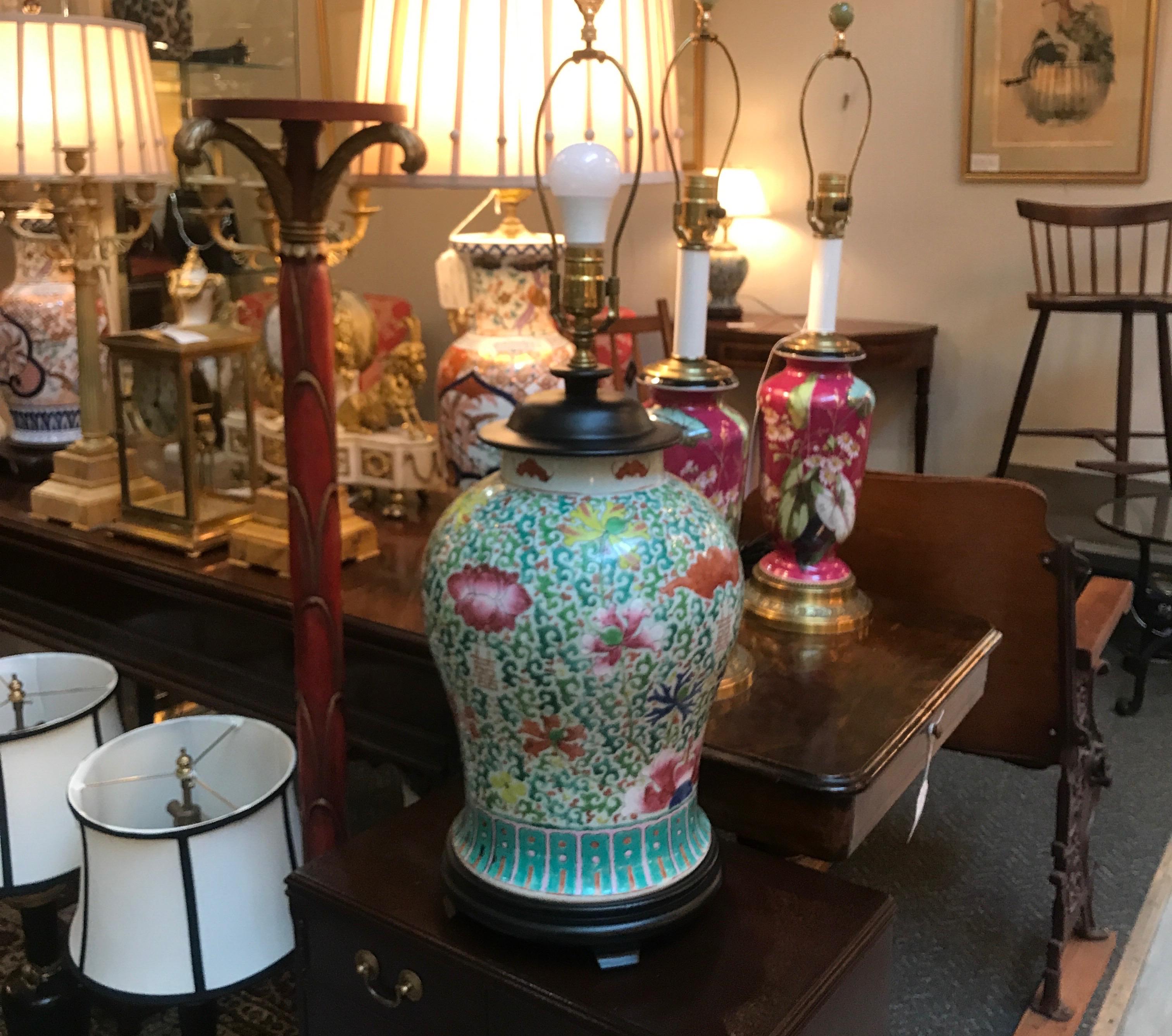 A large beautifully hand painted Chinese porcelain temple jar lamp. all-over decoration of leaves vines and peonies with a ebonized lid and base. The shade is for photographic purposes only and not included. 29 inches high to the top of the shade,