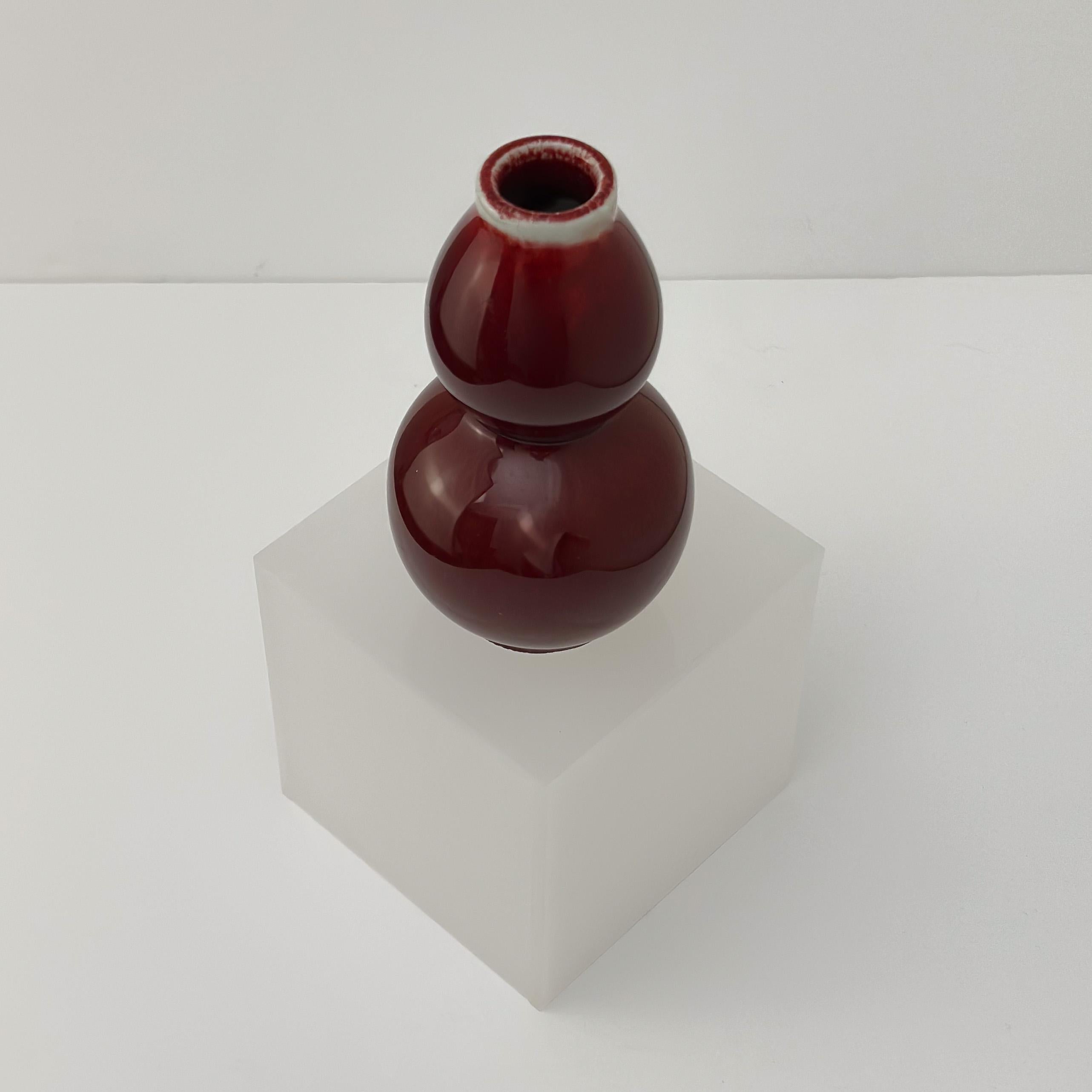 Un piccolo vaso cinese a doppia zucca, realizzato a mano in Cina, intorno agli anni '60. 

Rifinito con un ricco smalto rosso sangue, noto come Sang de Boeuf, questo pezzo incarna sia la tradizione cinese che la maestria. La forma a doppia zucca, da