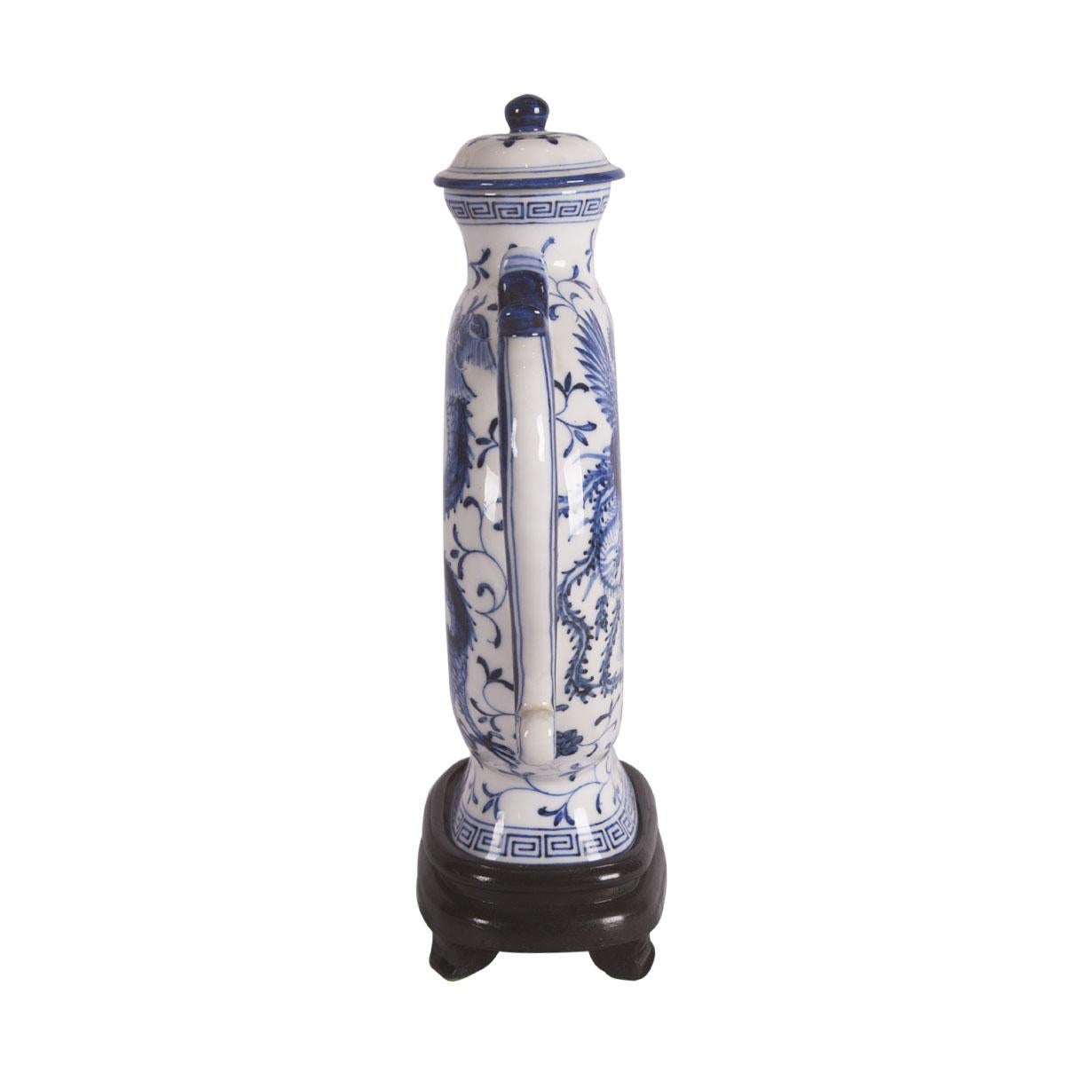 Made of porcelain, this Chinese wine pot is from the late 1950s and has traditional blue hand painted dragon designs through out the pot with stamping at the bottom of the wine pot. It also includes the matching wooden stand. Pot measures 11.50