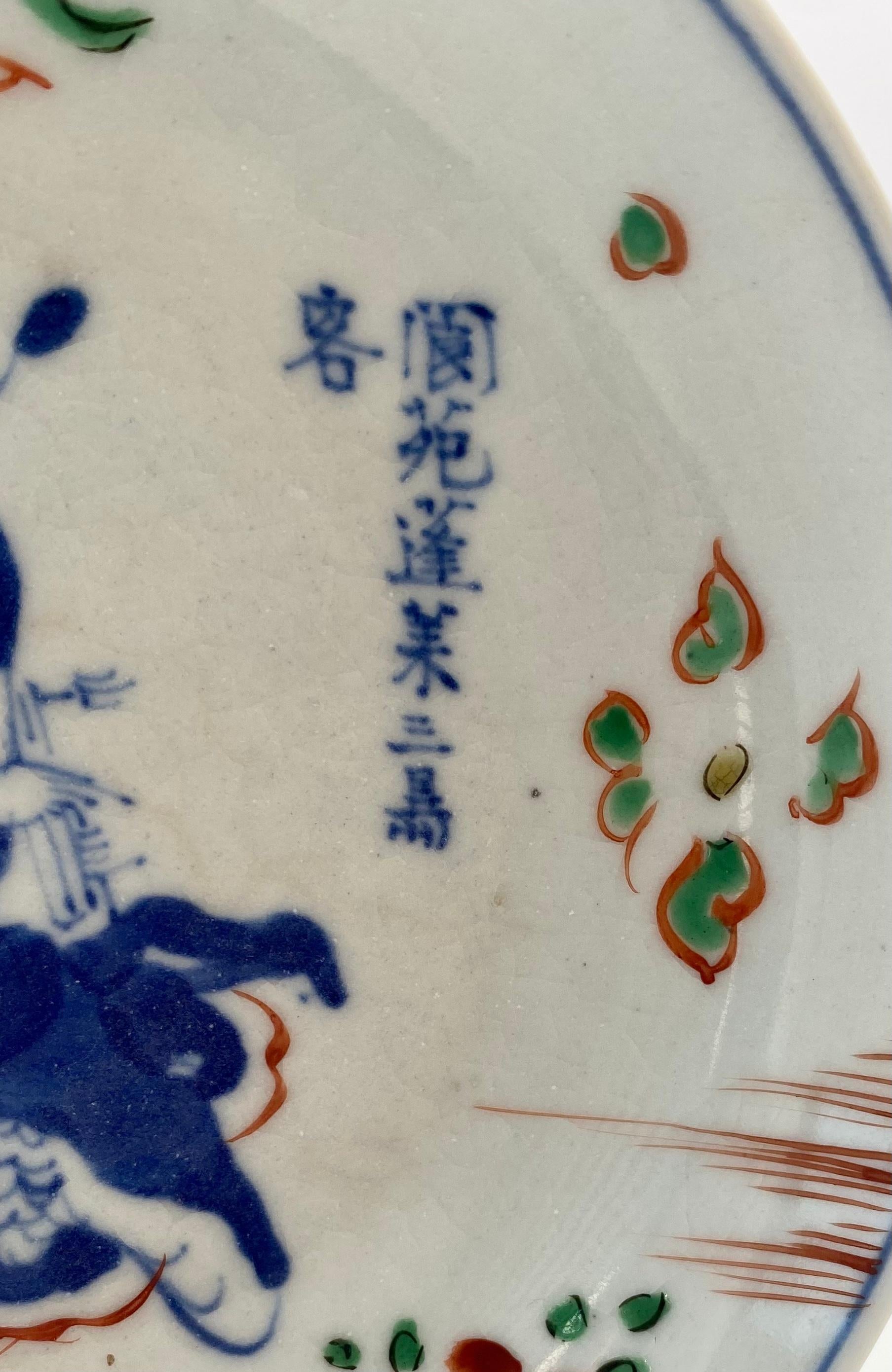 Chinese porcelain saucer dish, Tianqi mark and period (1621 – 1627). The circular dish, painted in underglaze blue and wucai enamels, with the Immortal, Cao Guojiu, holding clappers, and riding on clouds, above stylised flowering plants, and with an
