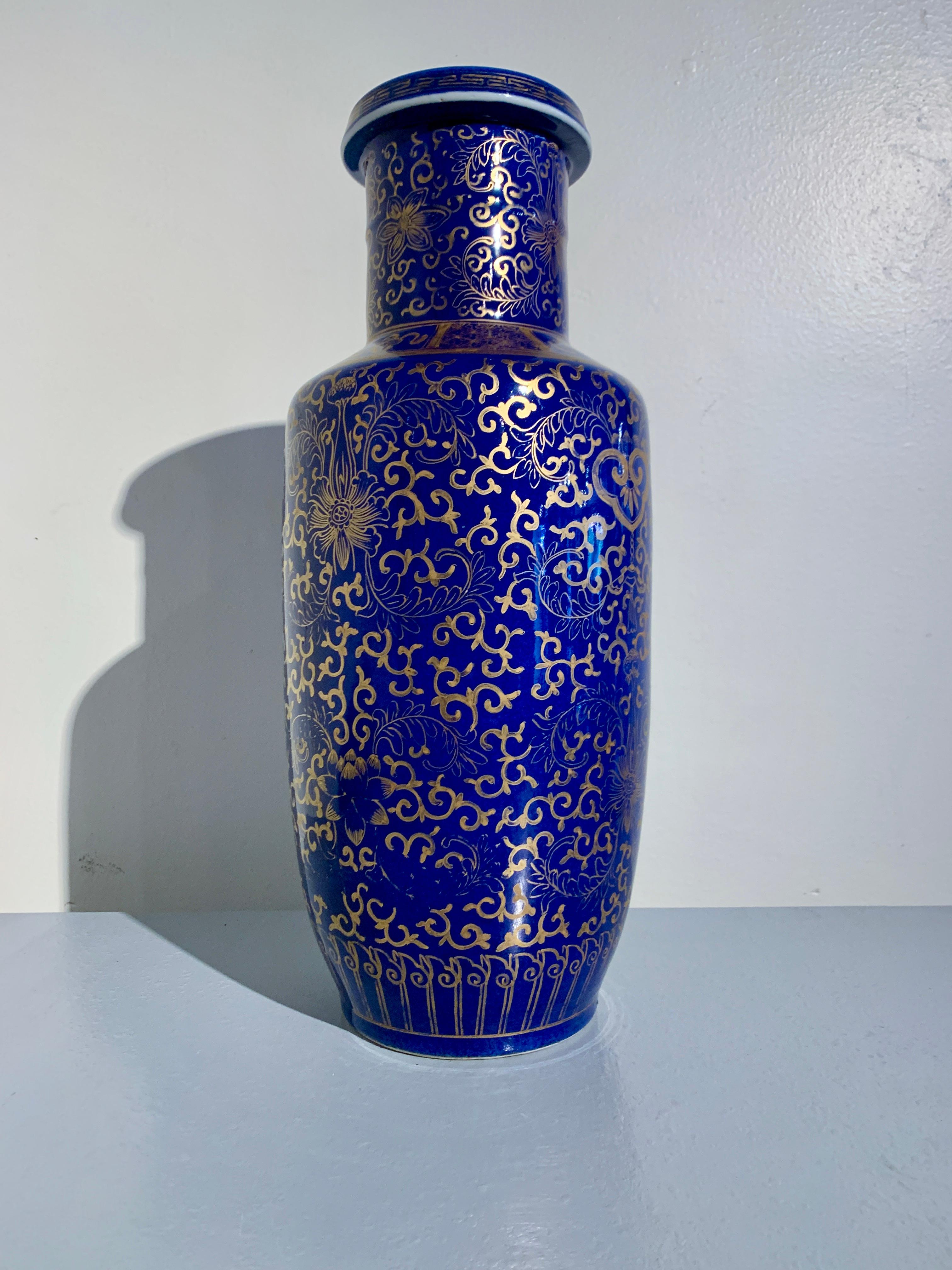 An impressive and opulent Chinese powder blue glazed porcelain rouleau vase with gilt painted decoration, very Late Qing Dynasty, circa 1900, China. 

The vase glazed in a deep and rich cobalt blue, known as powder blue, and boldly painted in