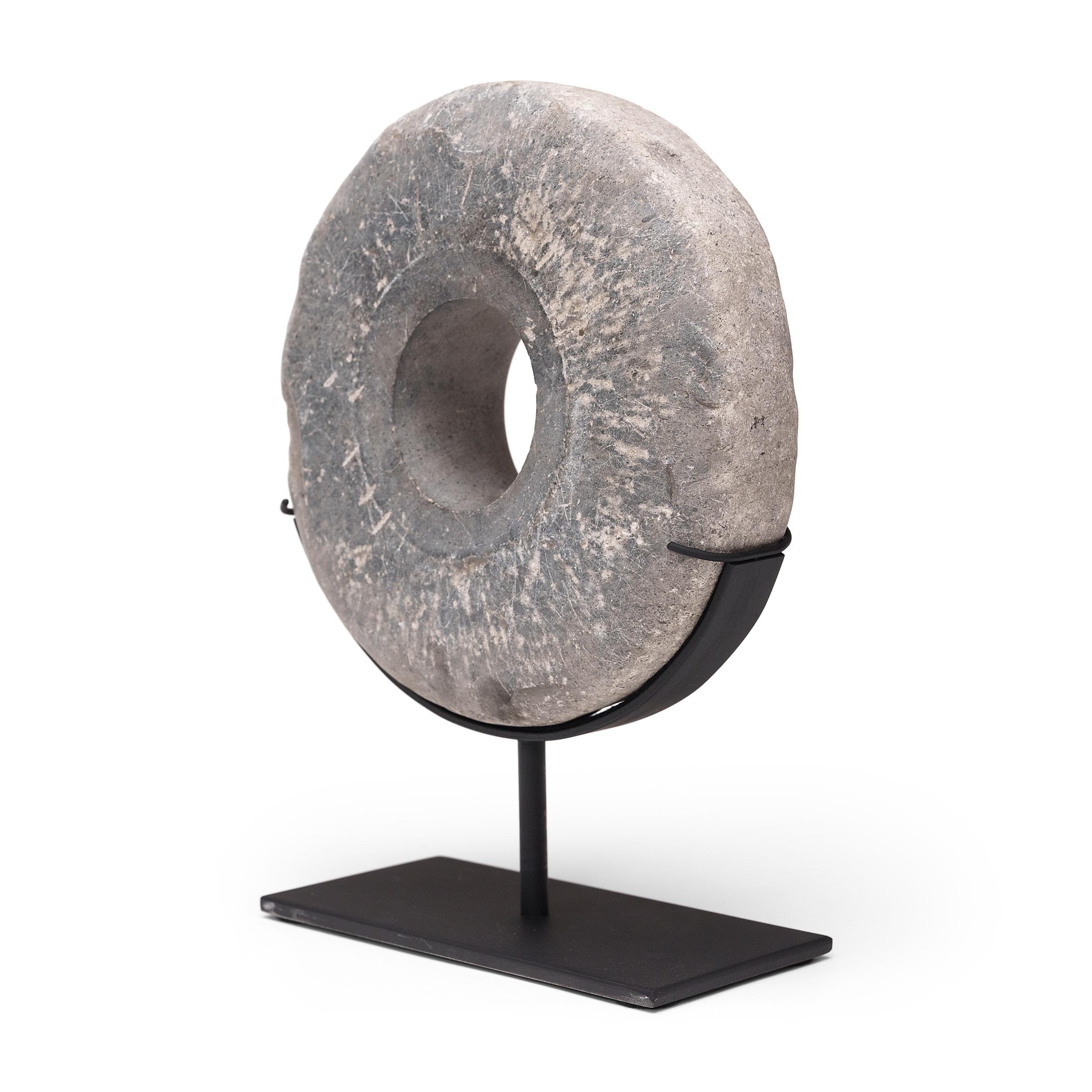 This round stone disc originated in Shanxi province as an early 20th-century threshing wheel. Secured to a wooden axel that ran through the center, the stone was rolled across stalks of wheat to separate the grain from the chaff, pulled by man or