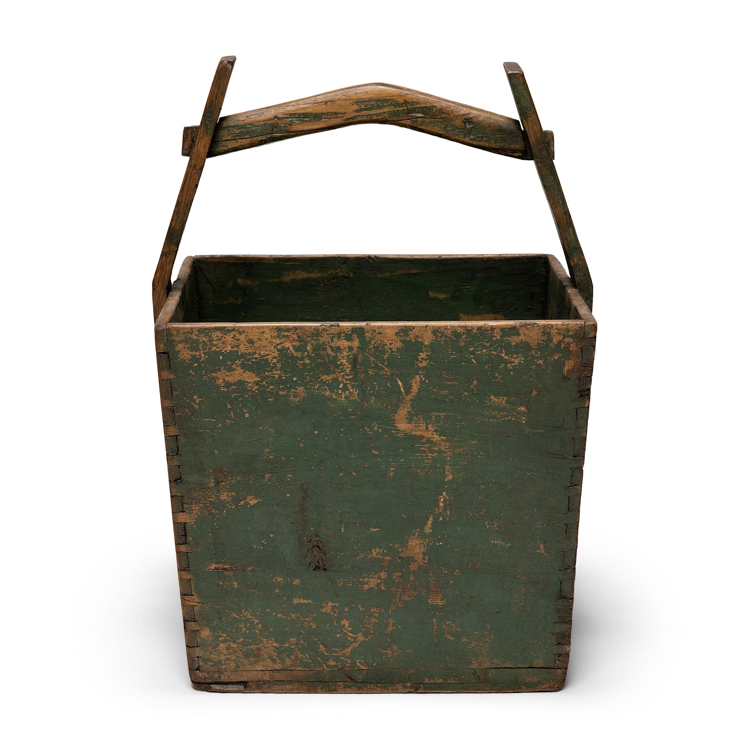 This hand-crafted wooden bucket was once used by farmers in Shanxi, China to transport their harvest of rice and grains over long distances. Counterbalanced by a second container, the pail would have been lifted by a pole threaded through the tall