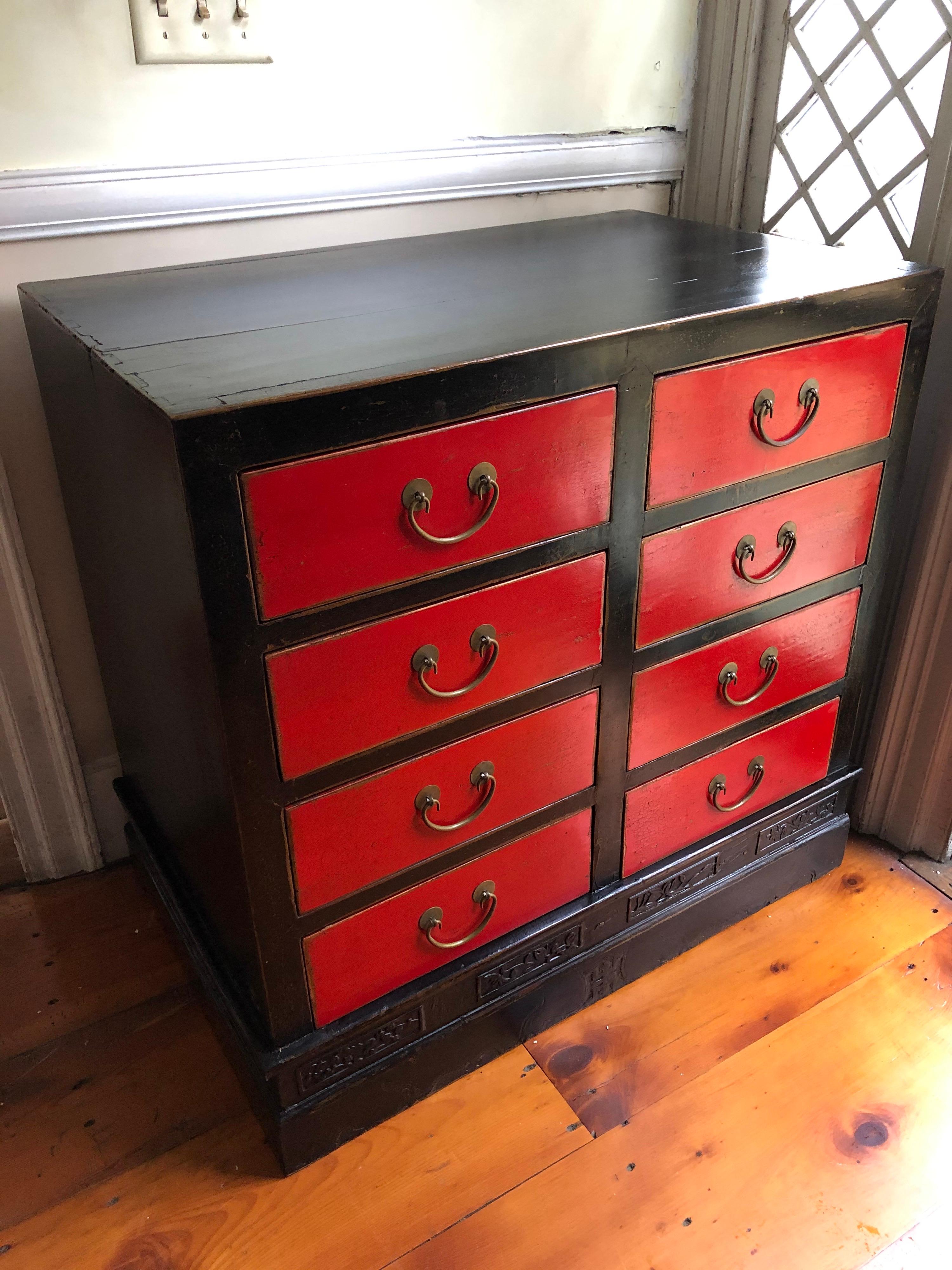 8-drawer Chinese provincial red and black lacquer chest of drawers. Brass drawer pulls. Each drawer marked in Chinese for placement nice carved detail along the base. From the Estate of Sir John Richardson.