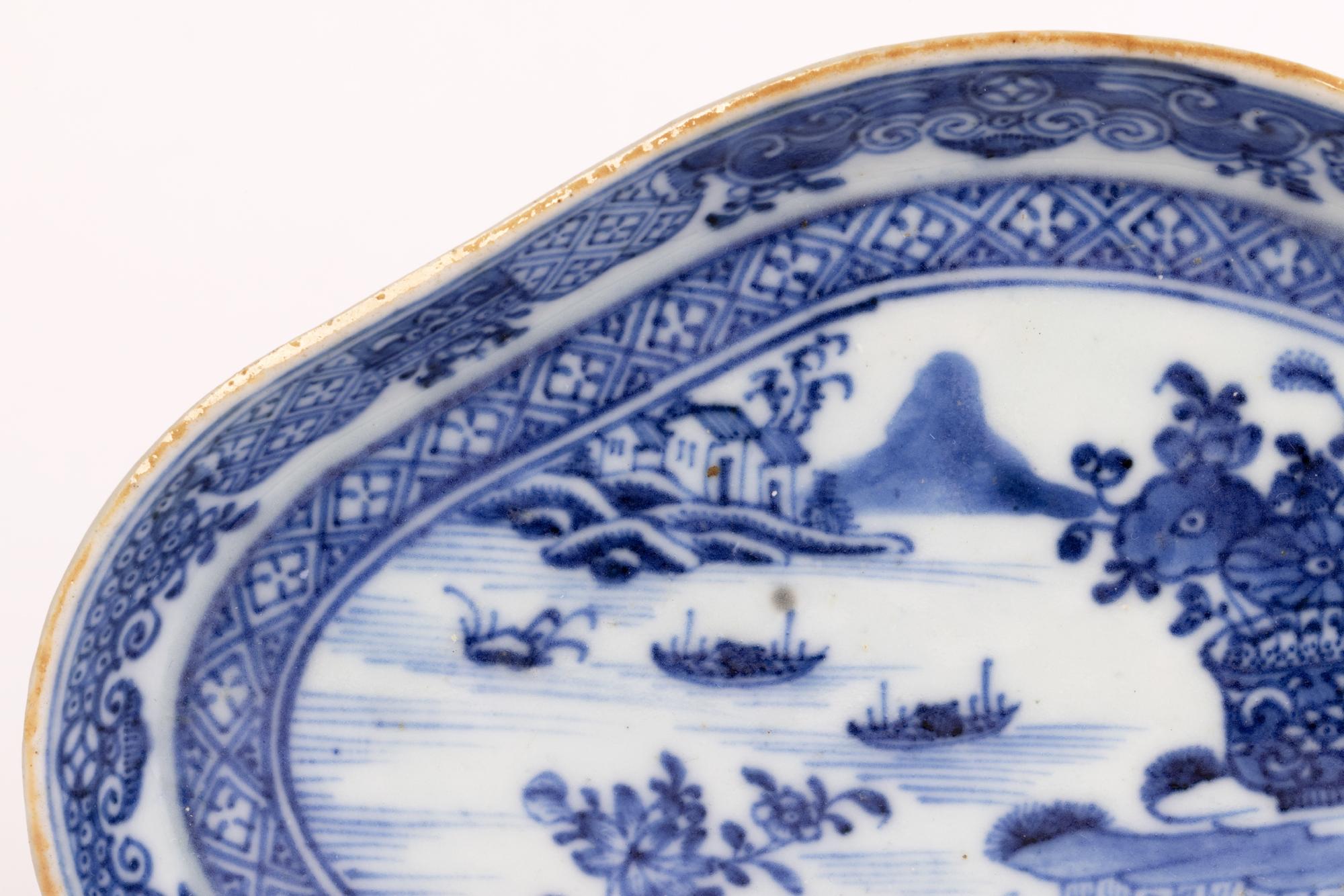 A fine antique Chinese Qianlong porcelain serving dish hand painted with a watery landscape and dating from the 18th century. The shaped oval dish stands on an unglazed flat base with a raised rim with the centre hand painted in blue on a white