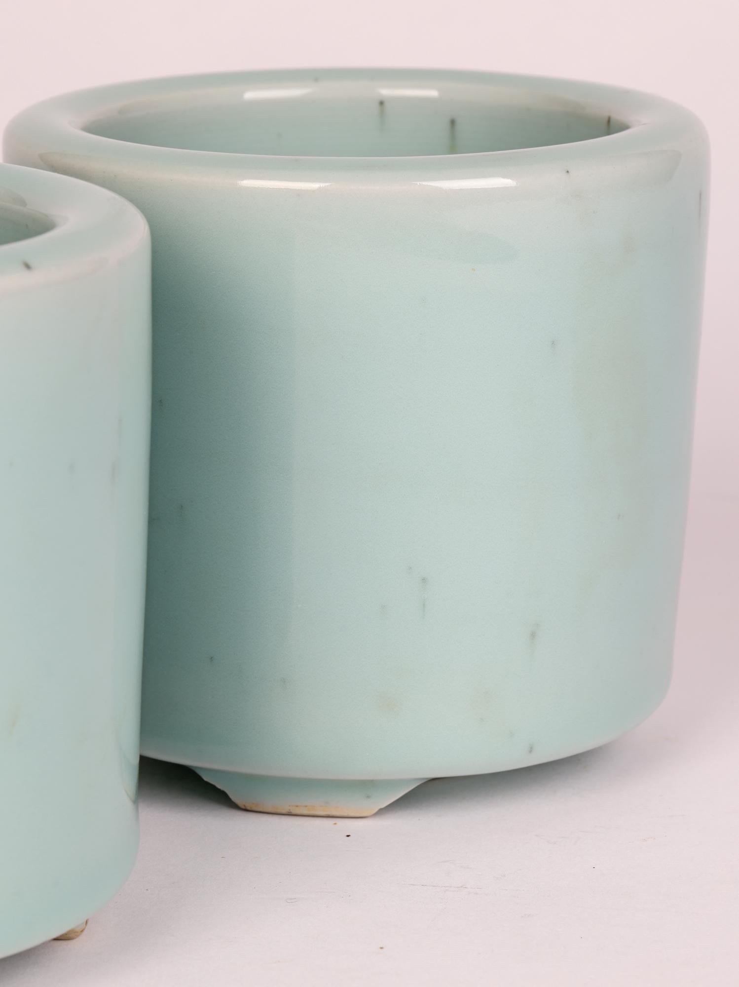 A stylish pair Chinese Qianlong mark pair celadon glazed porcelain brush pots believed to date from the latter 19th or early 20th century. The brush pots are heavily made standing raised on three small unglazed feet arranged around a narrow central