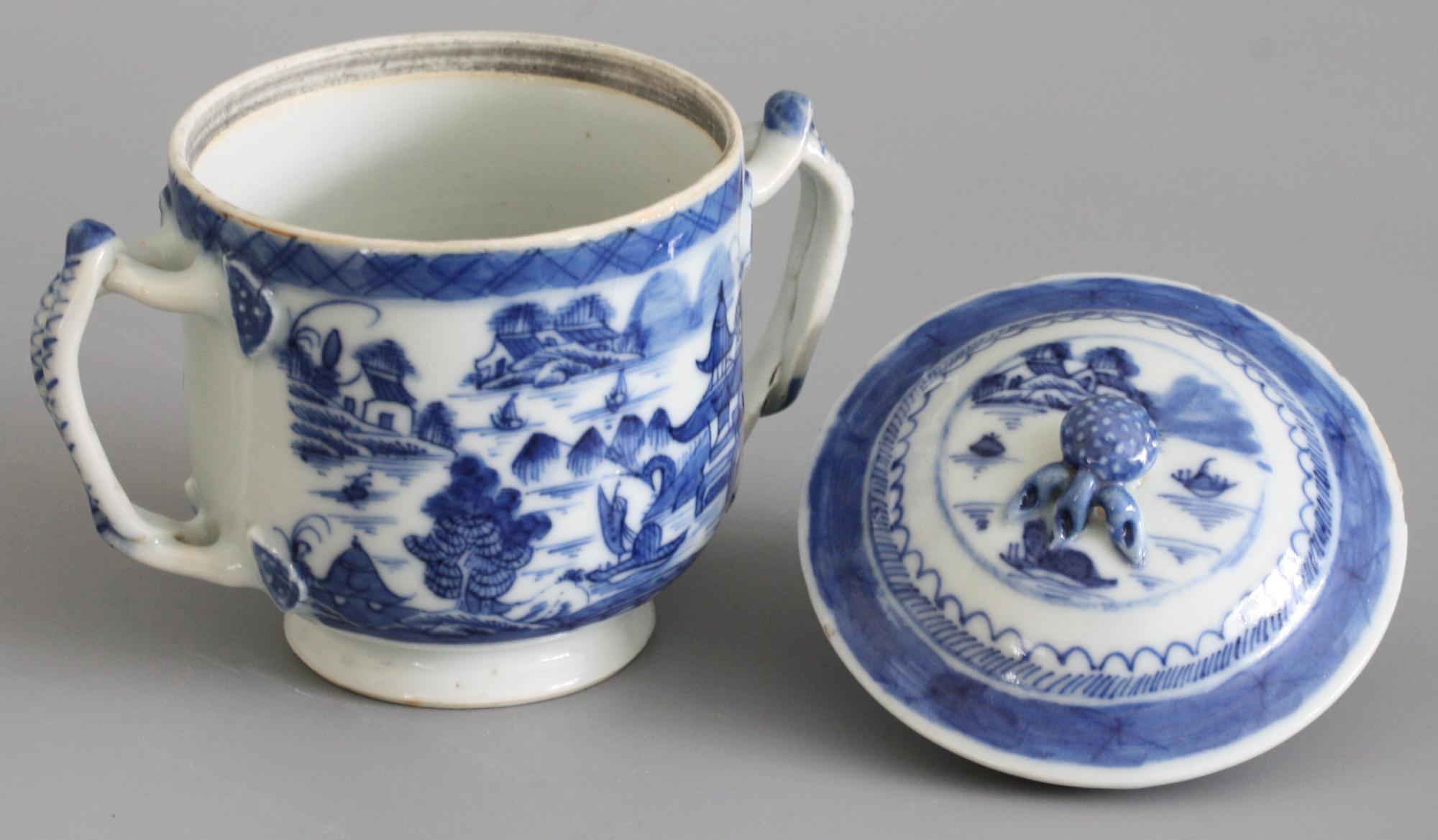 A fine antique Chinese Qianlong style porcelain twin handled lidded blue and white watery landscape painted cup probably dating to the 18th or possibly early 19th century. The cup stands raised on a narrow rounded foot with a cut and unglazed foot