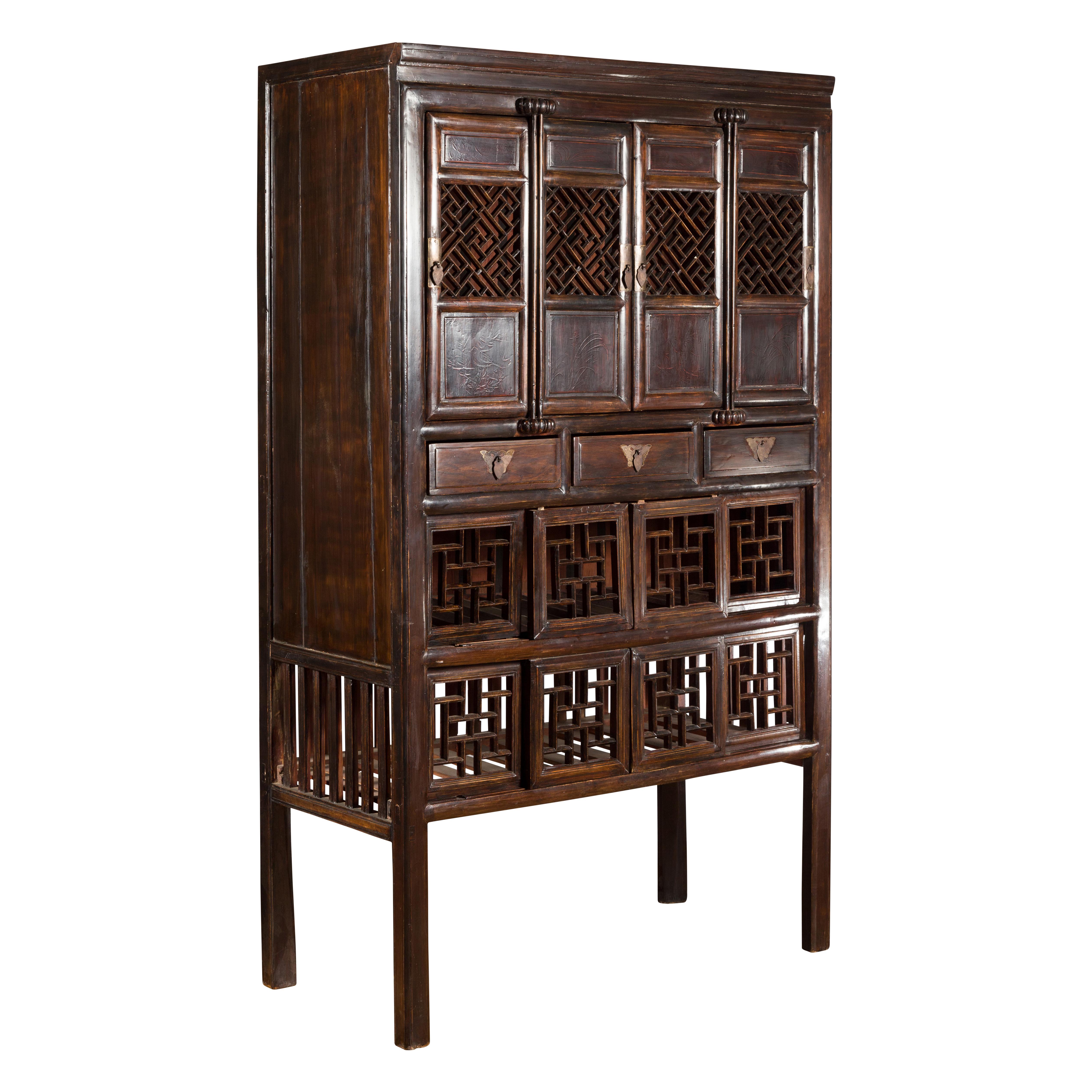 A Chinese Qing Dynasty period brown lacquered kitchen cabinet from the 19th century with geometric fretwork motifs, doors, drawers and butterfly hardware. Created in China during the Qing Dynasty, this tall Chinese cabinet features a linear