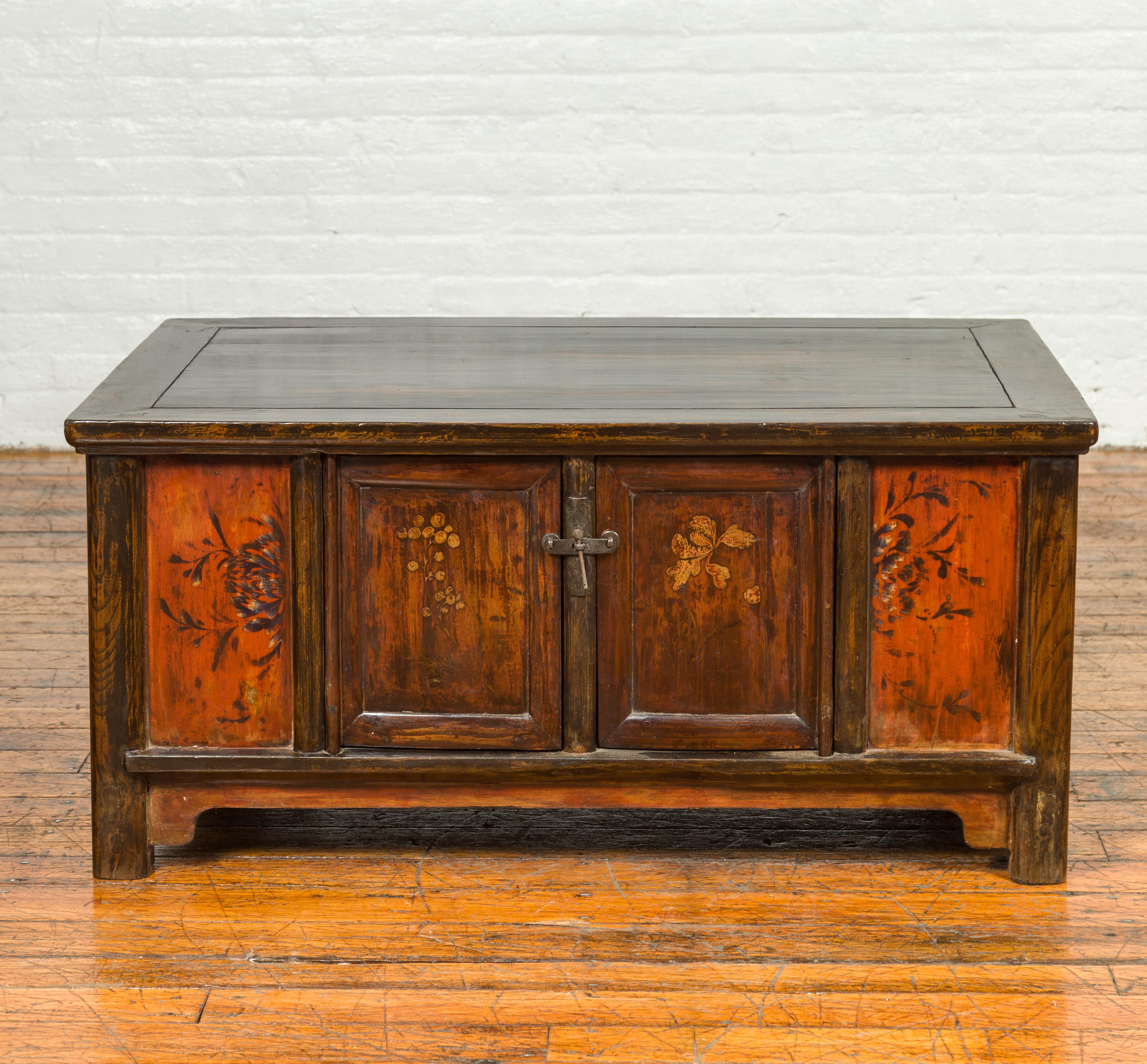 A Chinese Qing dynasty period low coffee table with storage from the 19th century, with hand painted floral decor. Crafted in China during the 19th century, this low coffee table charms us with its hand painted decor and convenient storage space. A