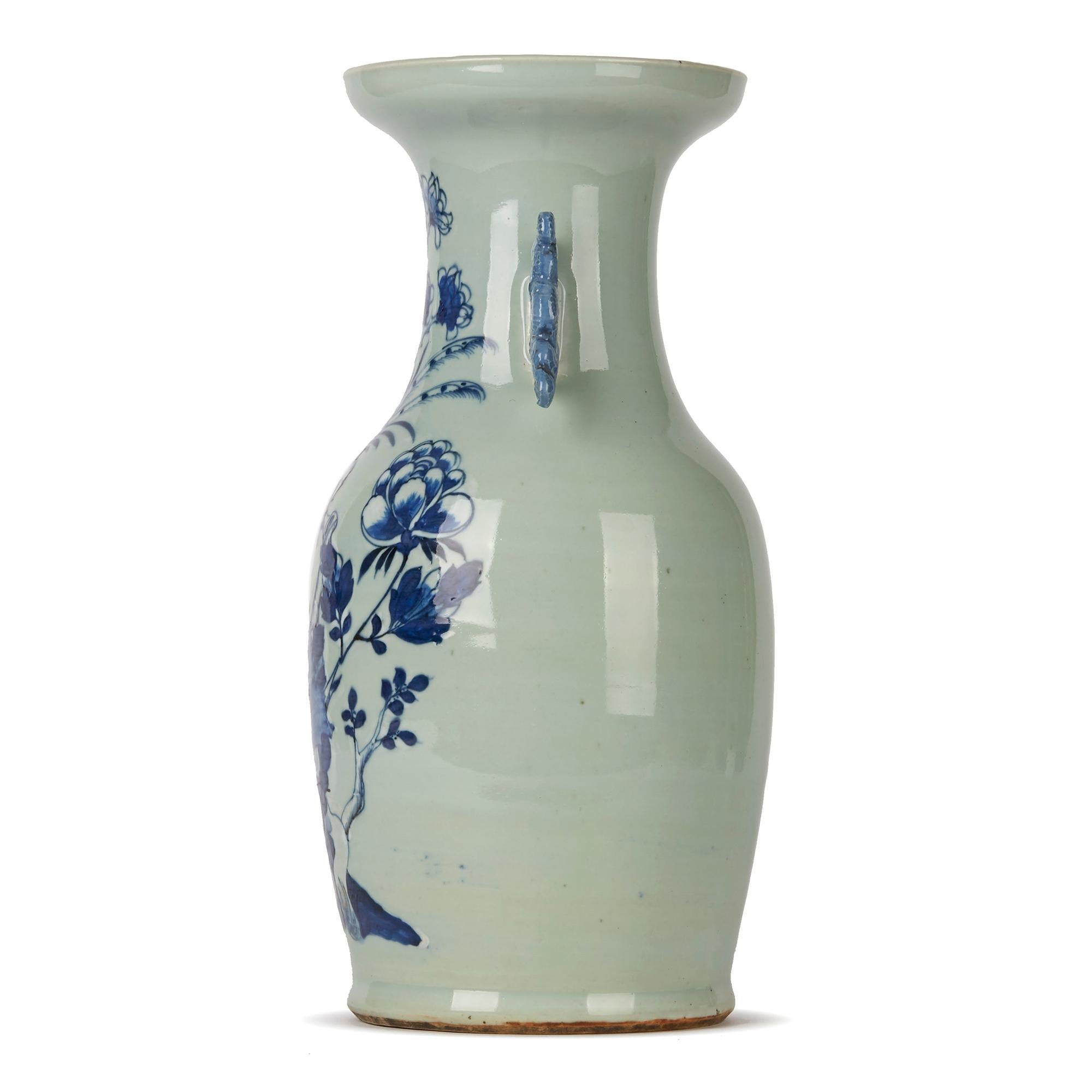 A stunning and large antique Chinese Qing twin handled porcelain vase decorated in blue and white with a bird perched on a branch amidst various flowering shrubs the scene painted against a celadon ground. The bulbous shaped vase has stylised dragon
