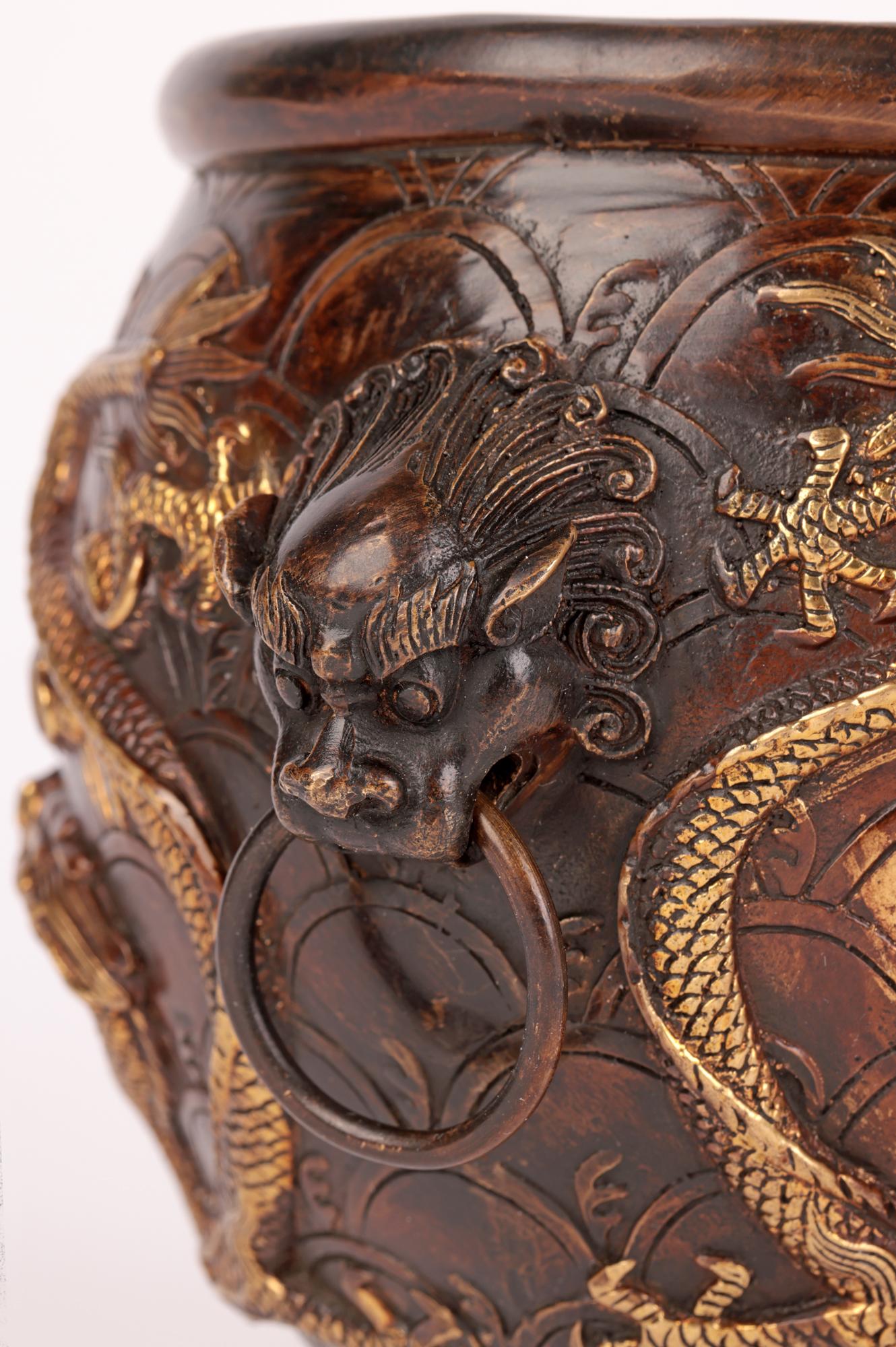 A very stylish Chinese Qing bronze twin handled bowl applied with gilded dragons chasing the flaming pearl and dating from the 19th Century. The bowl stands on a narrow flat round base and is of round bulbous shape with grotesque Foo dog head