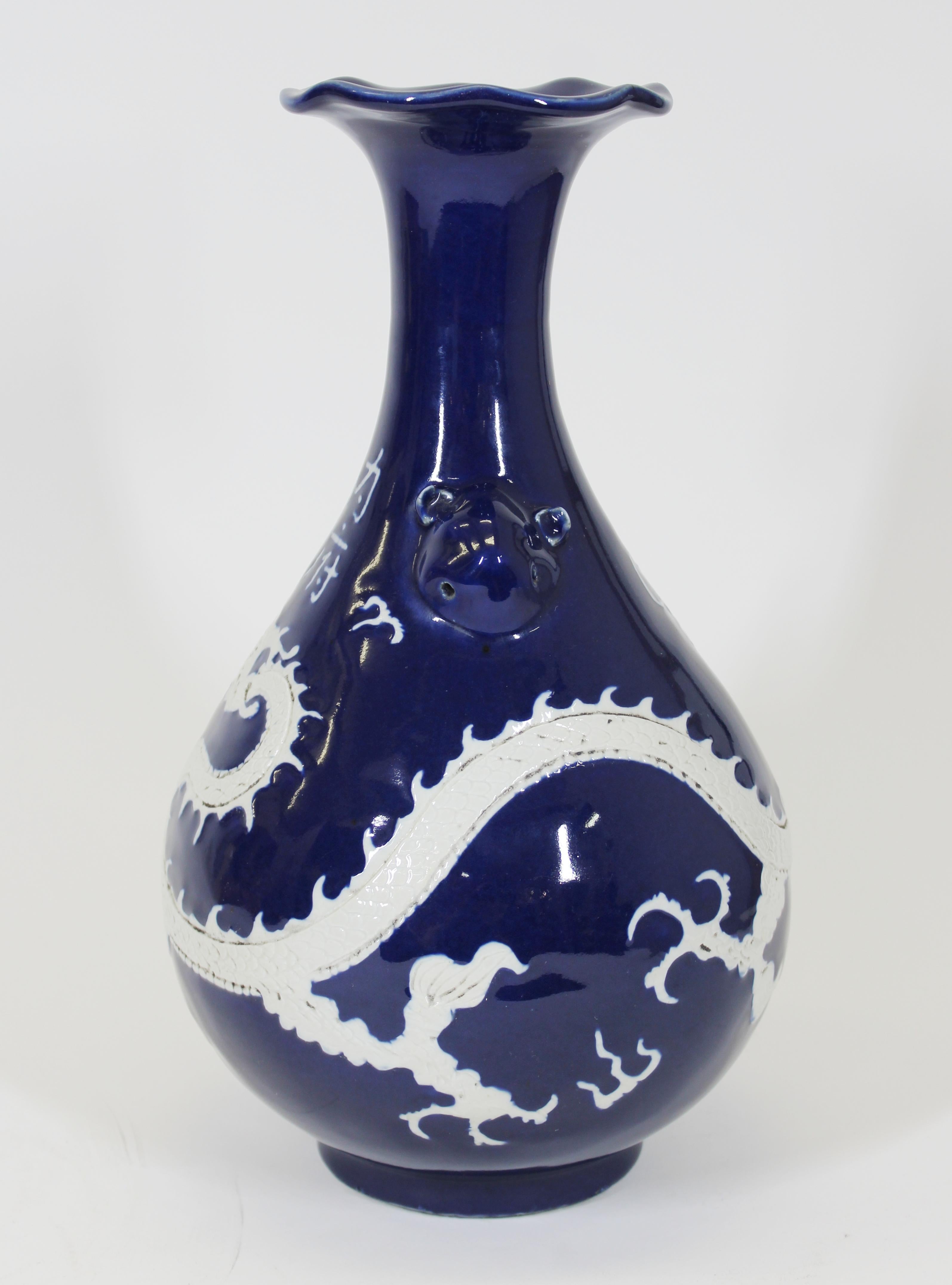 Chinese Qing dynasty baluster shape porcelain vase with rich cobalt blue glaze featuring a white dragon in high relief circling the vase. With stylized handles and a tulip opening. The Chinese characters on the front spell 'Imperial'. Made in China