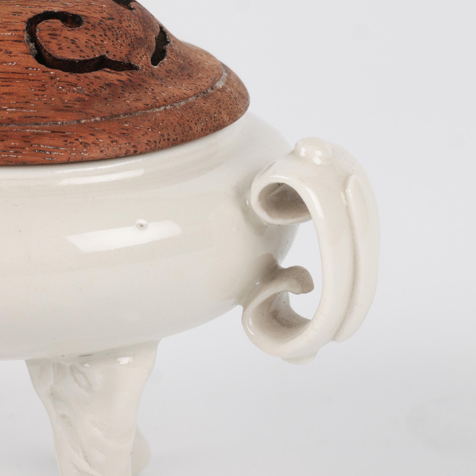 Très bel encensoir tripode en porcelaine blanche de Whiting, avec couvercle en bois dur et support associé, datant du 18/19ème siècle. Le petit encensoir repose sur trois pieds en forme de masque et de trompe d'éléphant qui soutiennent un corps