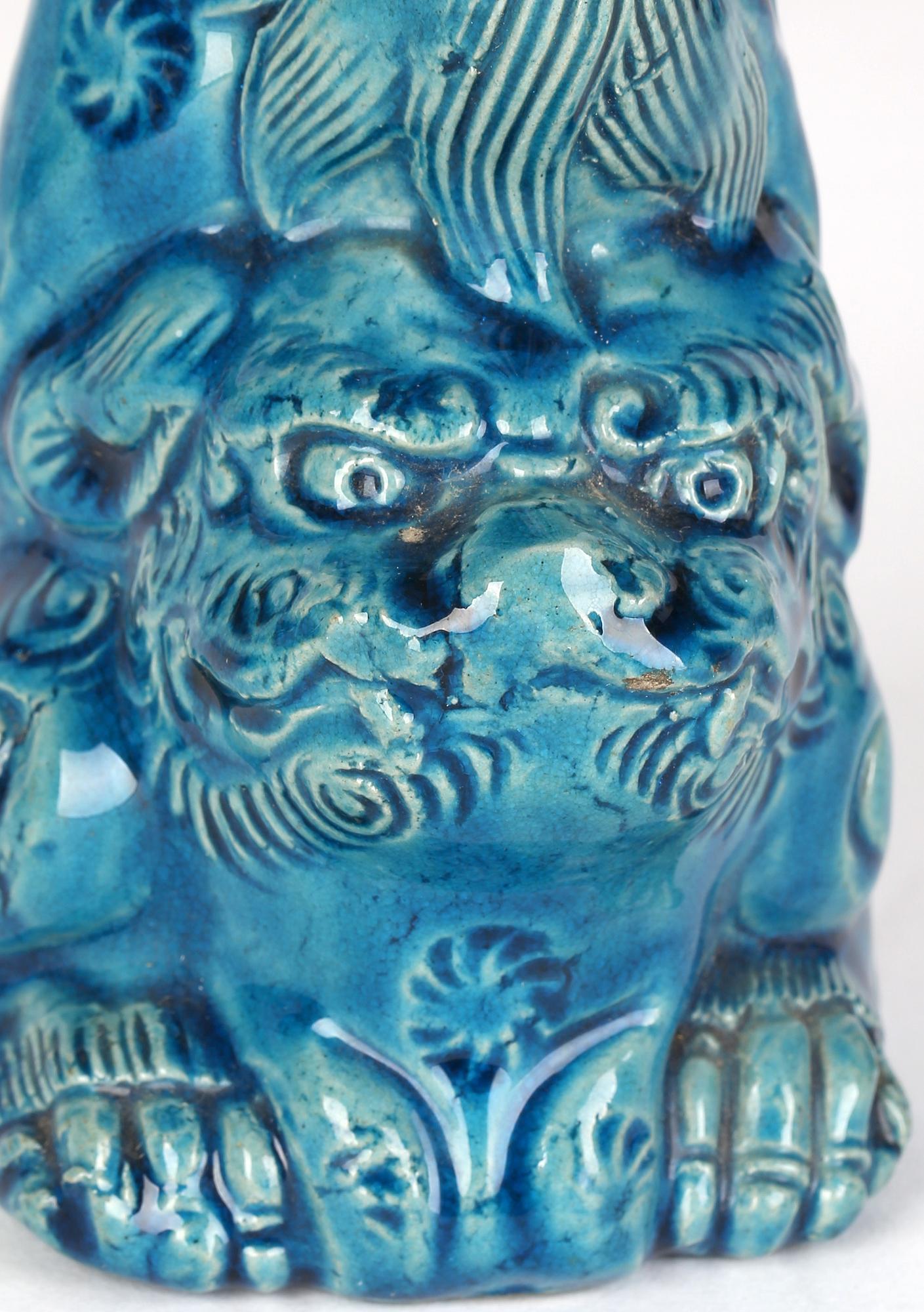 A stylish antique Chinese Qing porcelain vase modeled as a seated Foo Dog supporting an urn shaped vase on his hind legs dating from the 19th century. The vase is heavily pottery and well modeled with good detail and is decorated in turquoise
