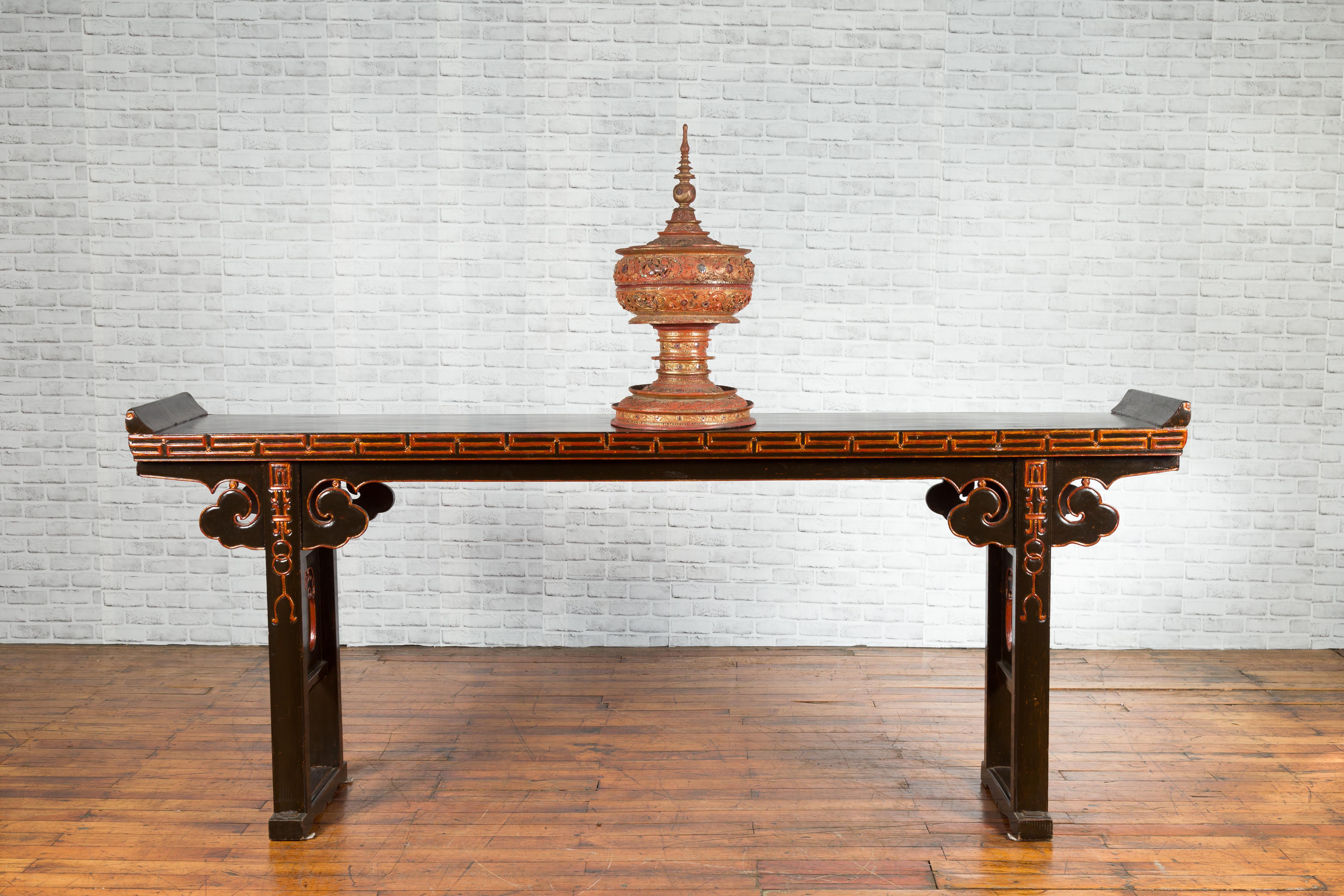 A Chinese Qing dynasty period Shandong long black lacquered altar console table from the late 19th century, with gold rubbed details and everted flanges. Created in Northeastern China during the Qing Dynasty, this long elm console table made in the