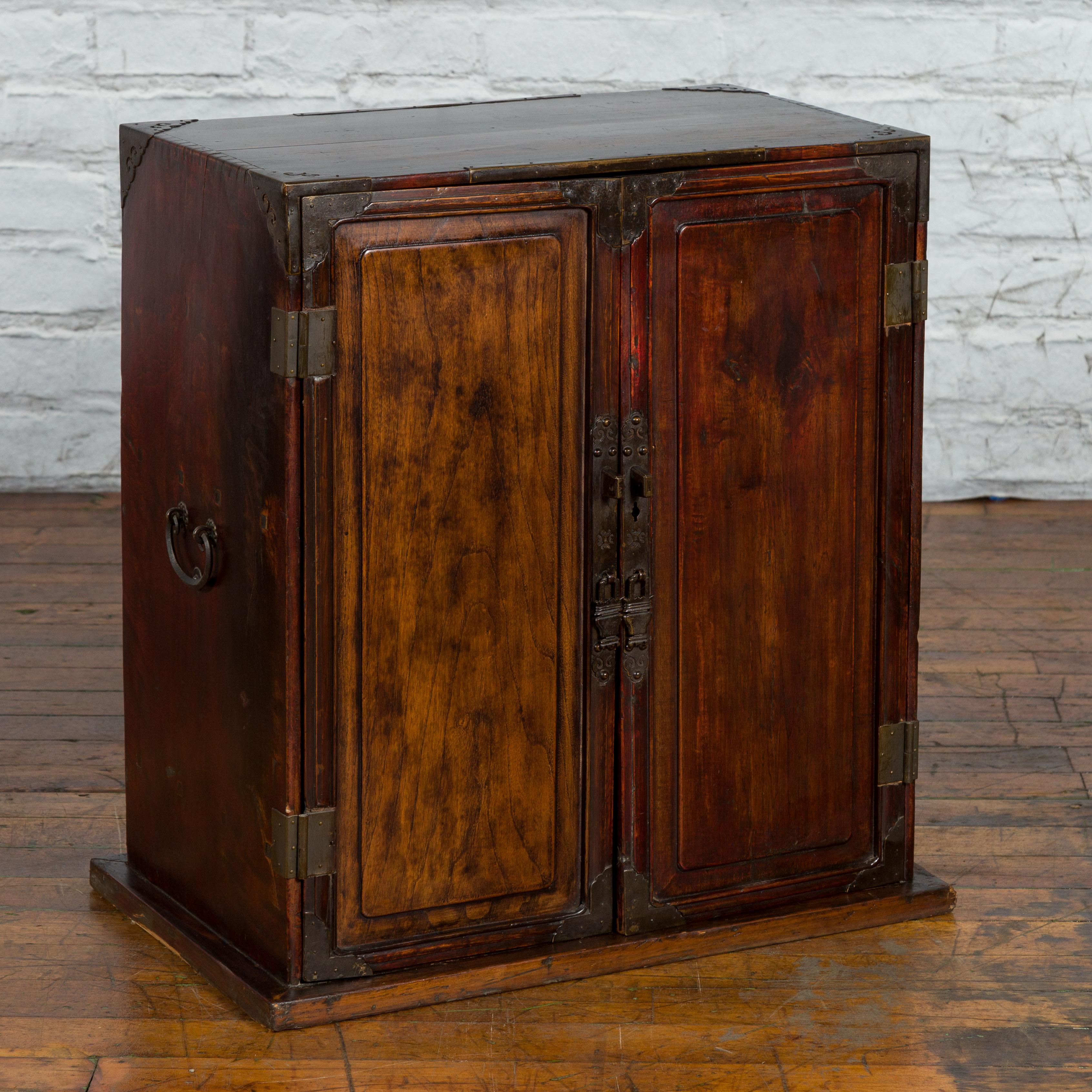 An antique Chinese Qing Dynasty period bedside cabinet from the 19th century, with two doors and brass hardware. Created in China during the Qing Dynasty period, this bedside cabinet features a rectangular planked top adorned with ornate brass