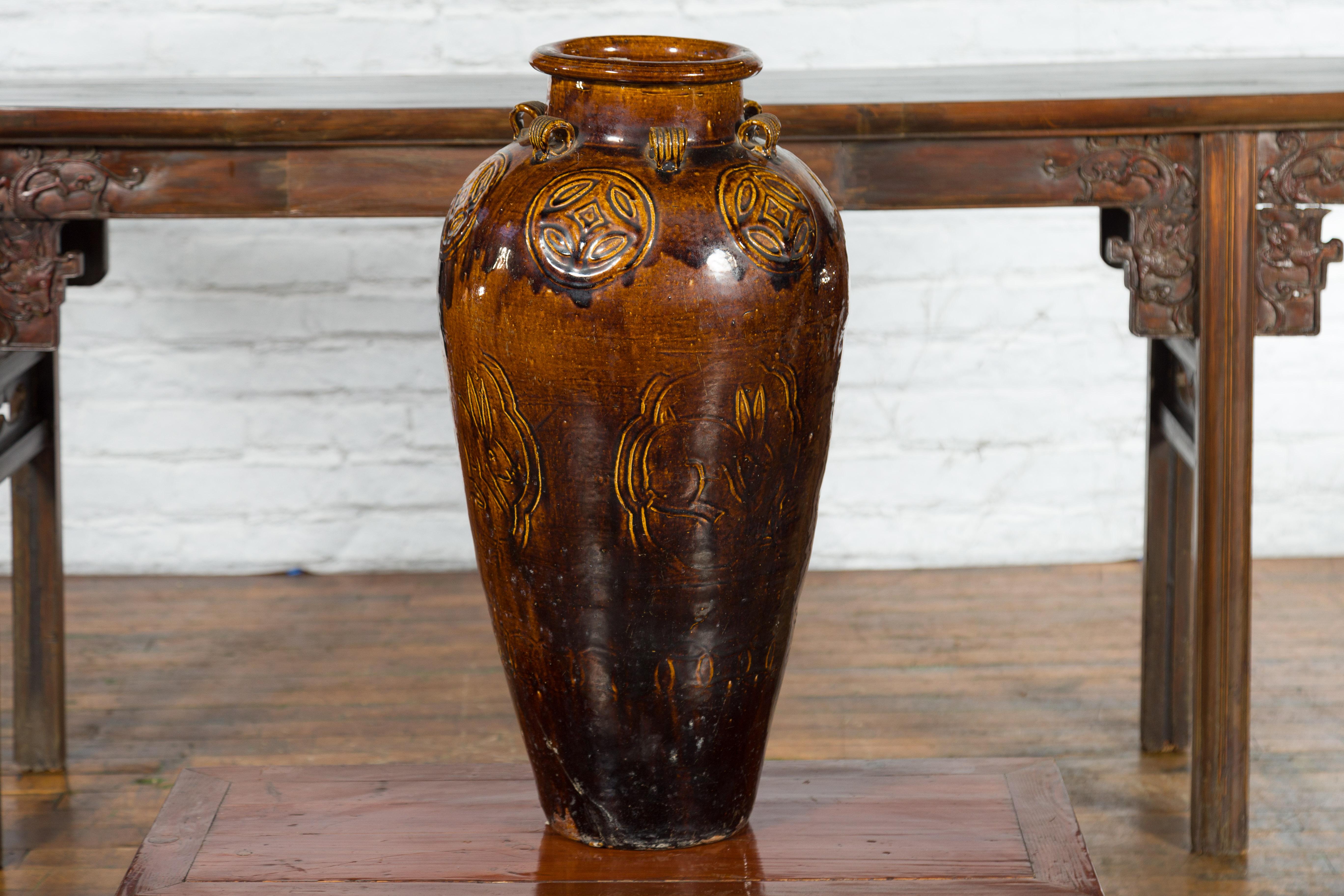 A large antique Chinese Qing Dynasty period brown glazed jar from the 19th century with petite loop handles, geometric medallions and rabbit motifs. Created in China during the 19th century, this vase features a narrow neck topped by a thick lip