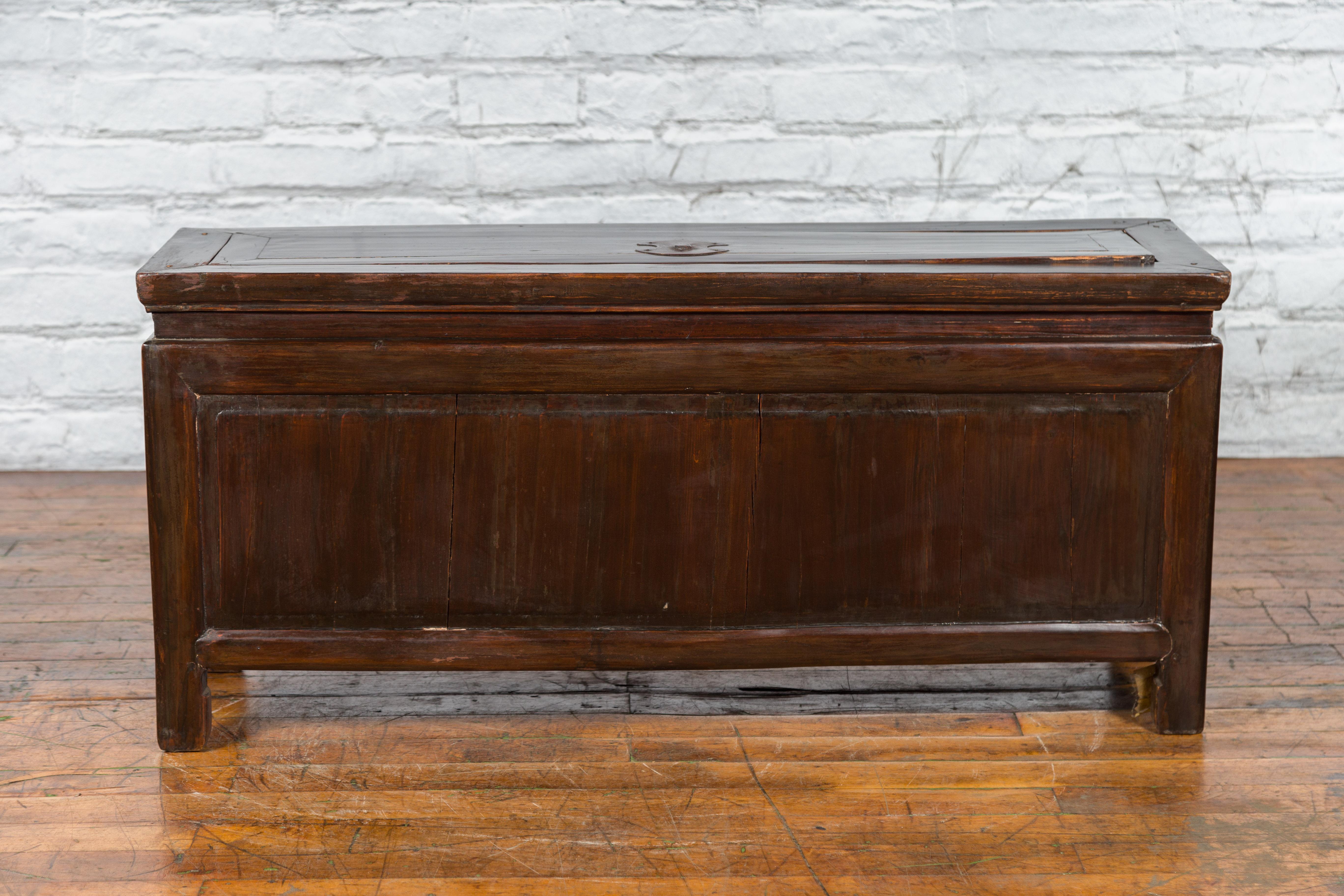 A Chinese antique Qing Dynasty period coffer from the 19th century, with brown lacquer, brass hardware, horse hoof feet and rustic appeal. Created in China during the Qing Dynasty period in the 19th century, this coffer features a long rectangular
