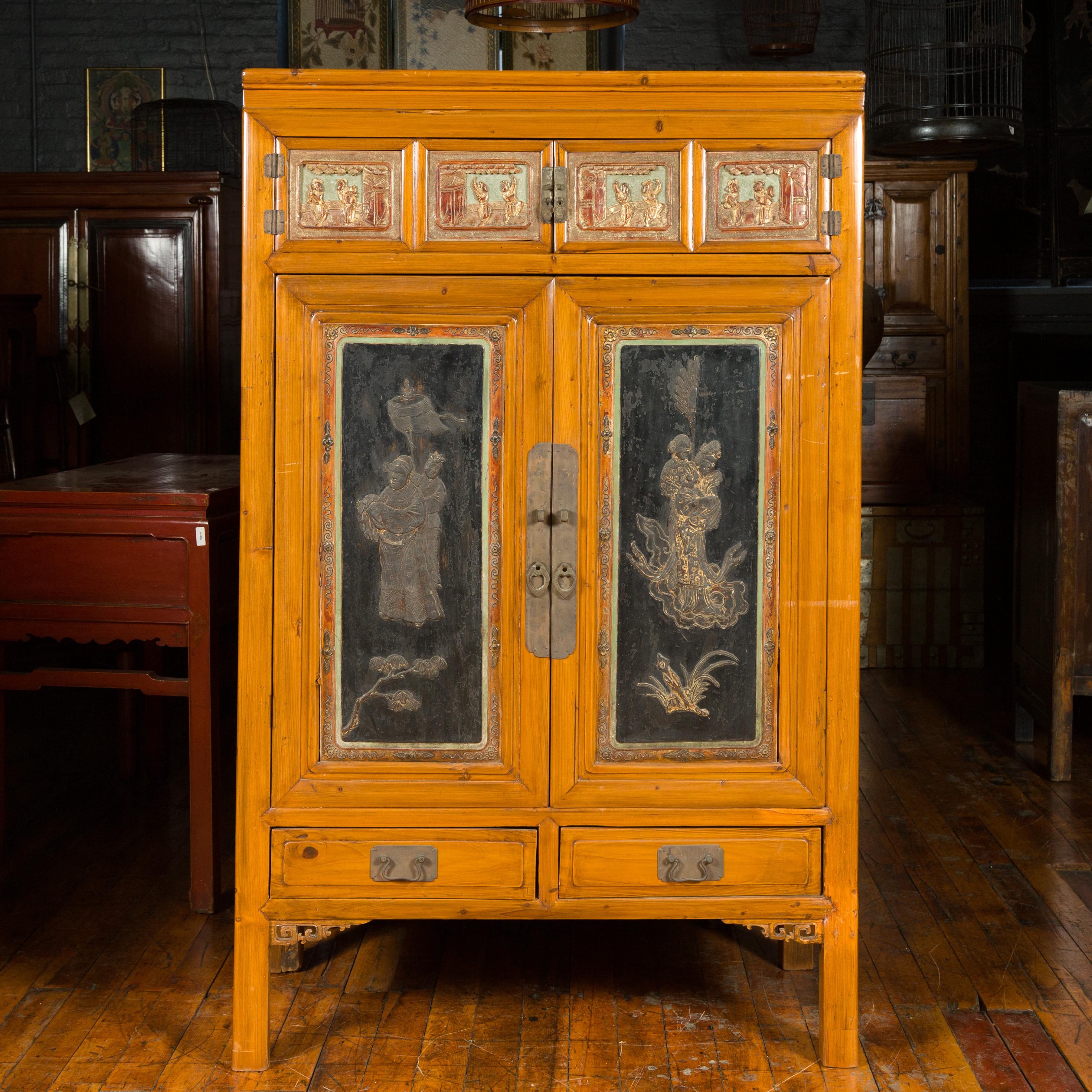 A Chinese Qing dynasty period cabinet from the 19th century, with carved panels depicting Guanyin and Daoist immortals. Created in China during the Qing dynasty, this 19th century cabinet attracts our attention with its beautifully contrasting