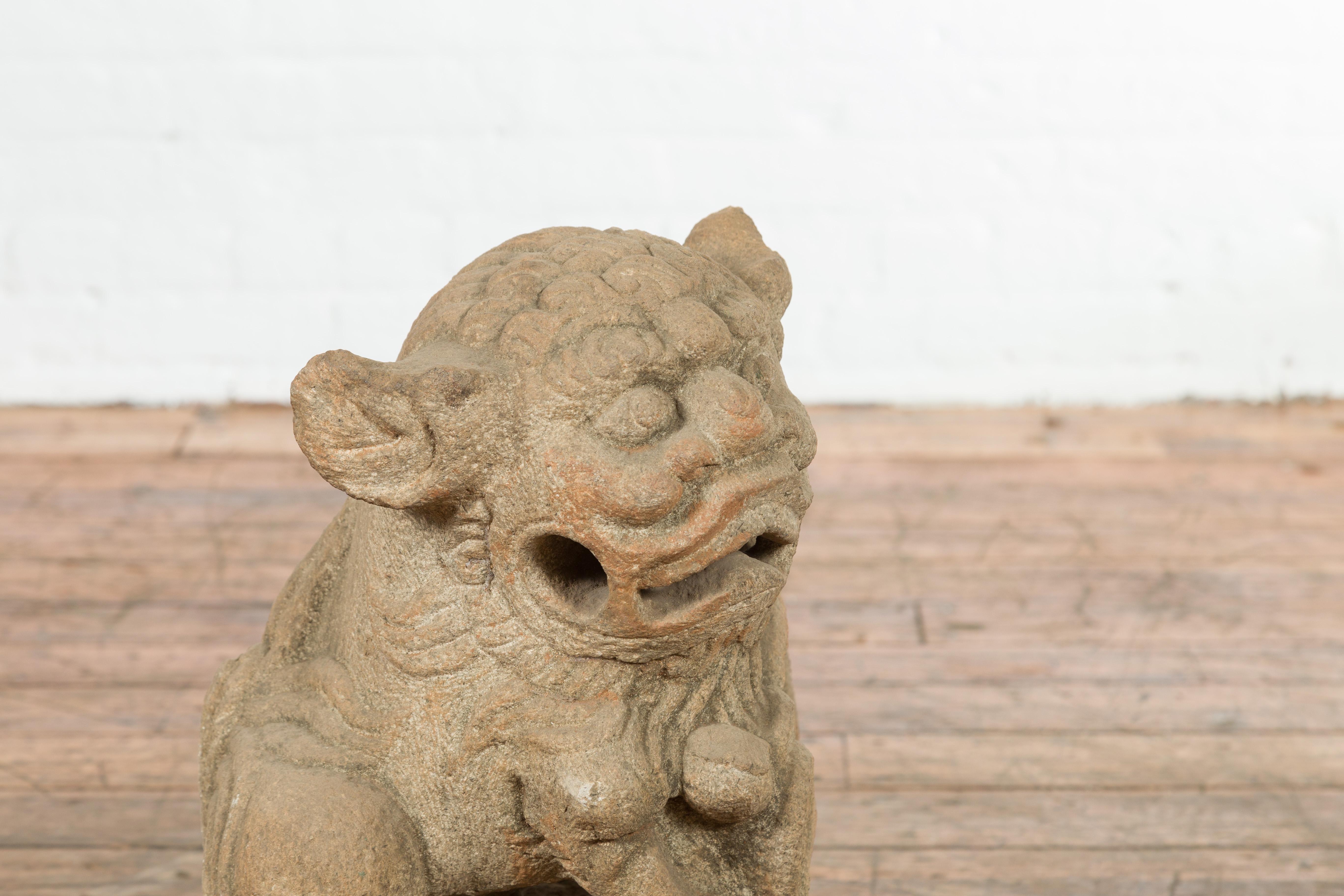 A Chinese Qing Dynasty period carved stone foo dog guardian lion from the 19th century, on square base. Created in China during the Qing Dynasty, this stone sculpture features a guardian lion sitting on a square base. The lion showcases an