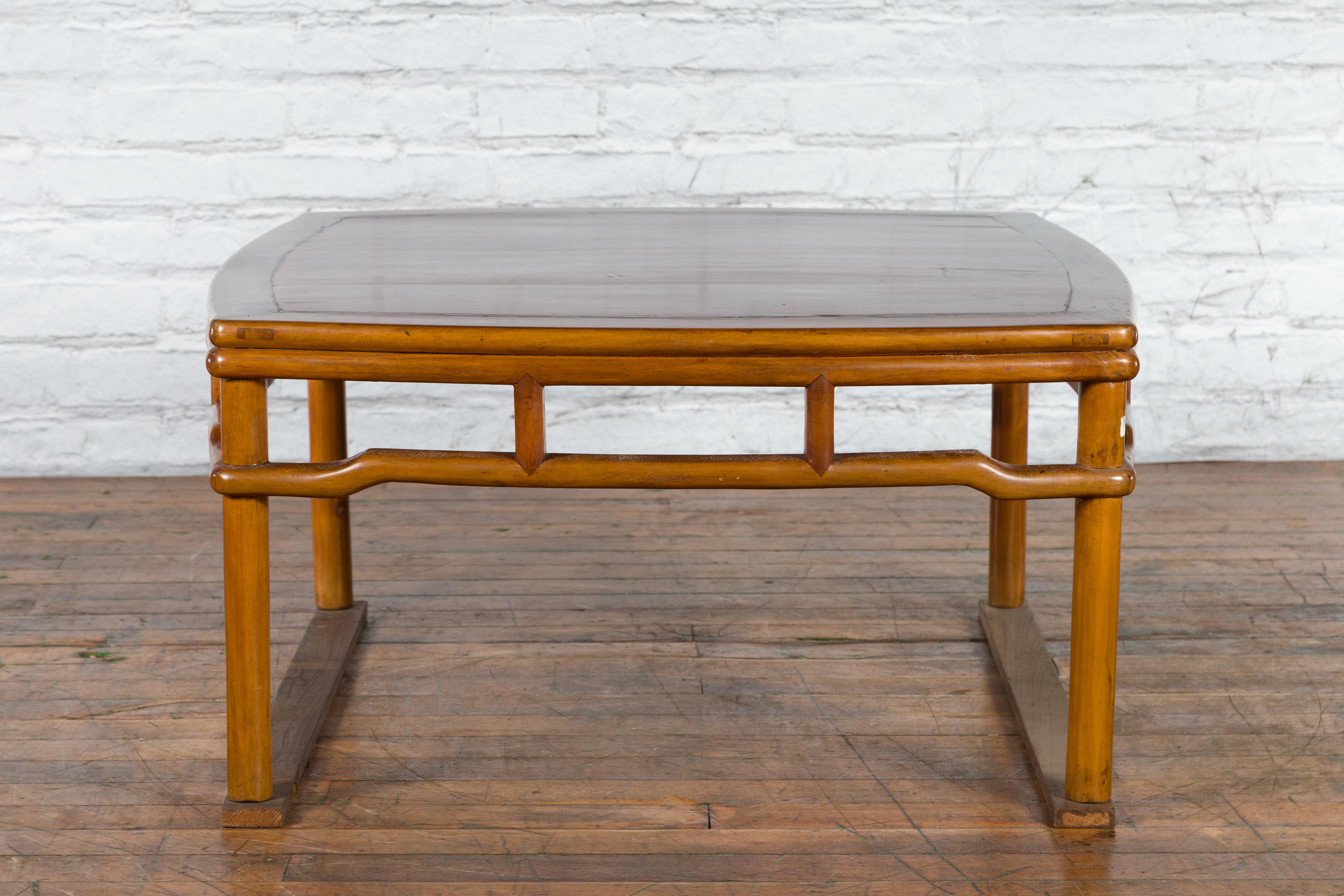 A Chinese Qing Dynasty period antique coffee table from the 19th century, with square top, pillar strut motifs, humpback stretchers and cylindrical legs. Created in China during the Qing Dynasty in the 19th century, this wooden coffee table features