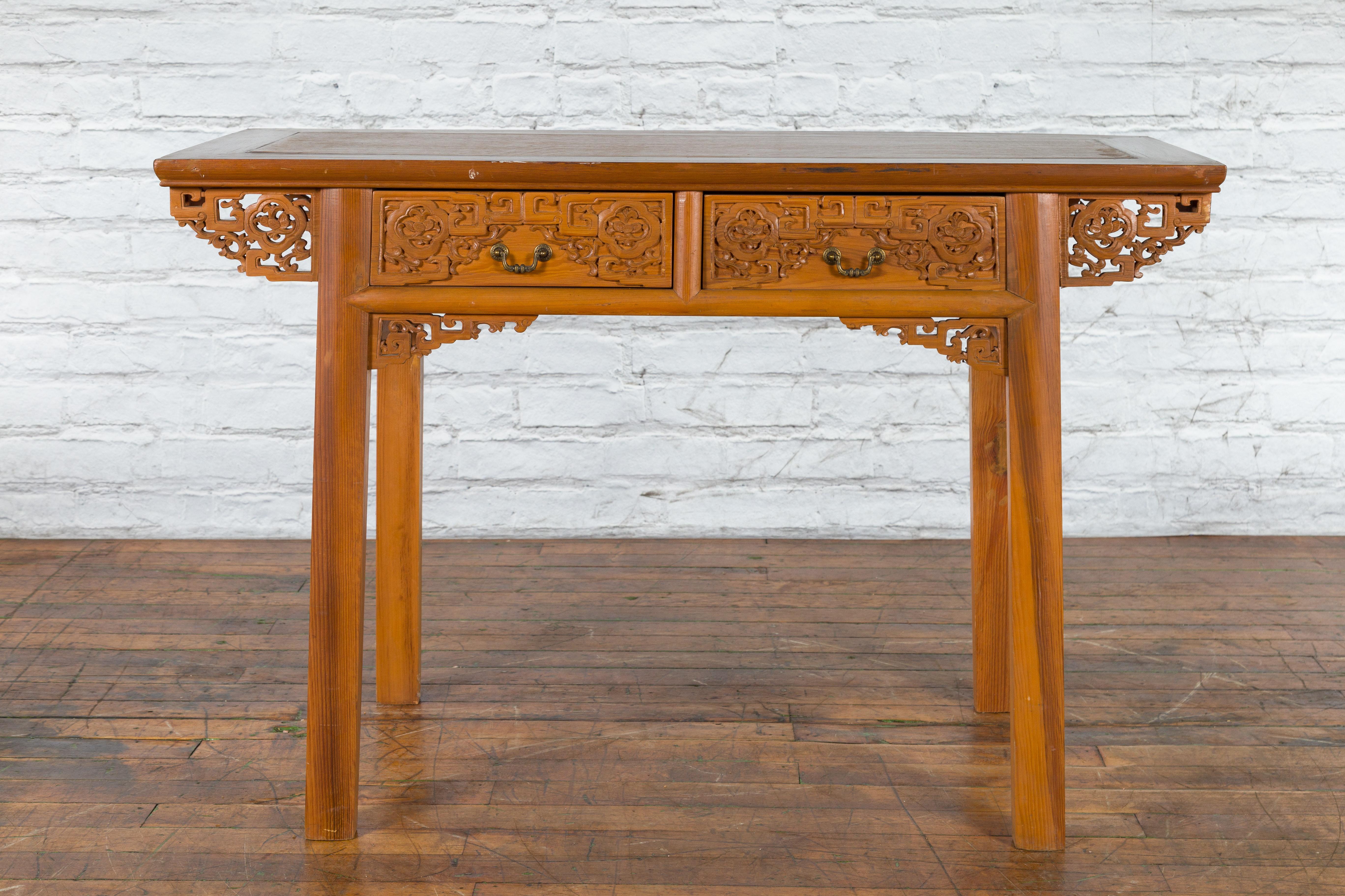 A Chinese Qing Dynasty period wooden desk from the 19th century with two carved drawers and fretwork motifs. Created in China during the Qing Dynasty in the 19th century, this exquisite wooden desk features a rectangular two-toned top with central