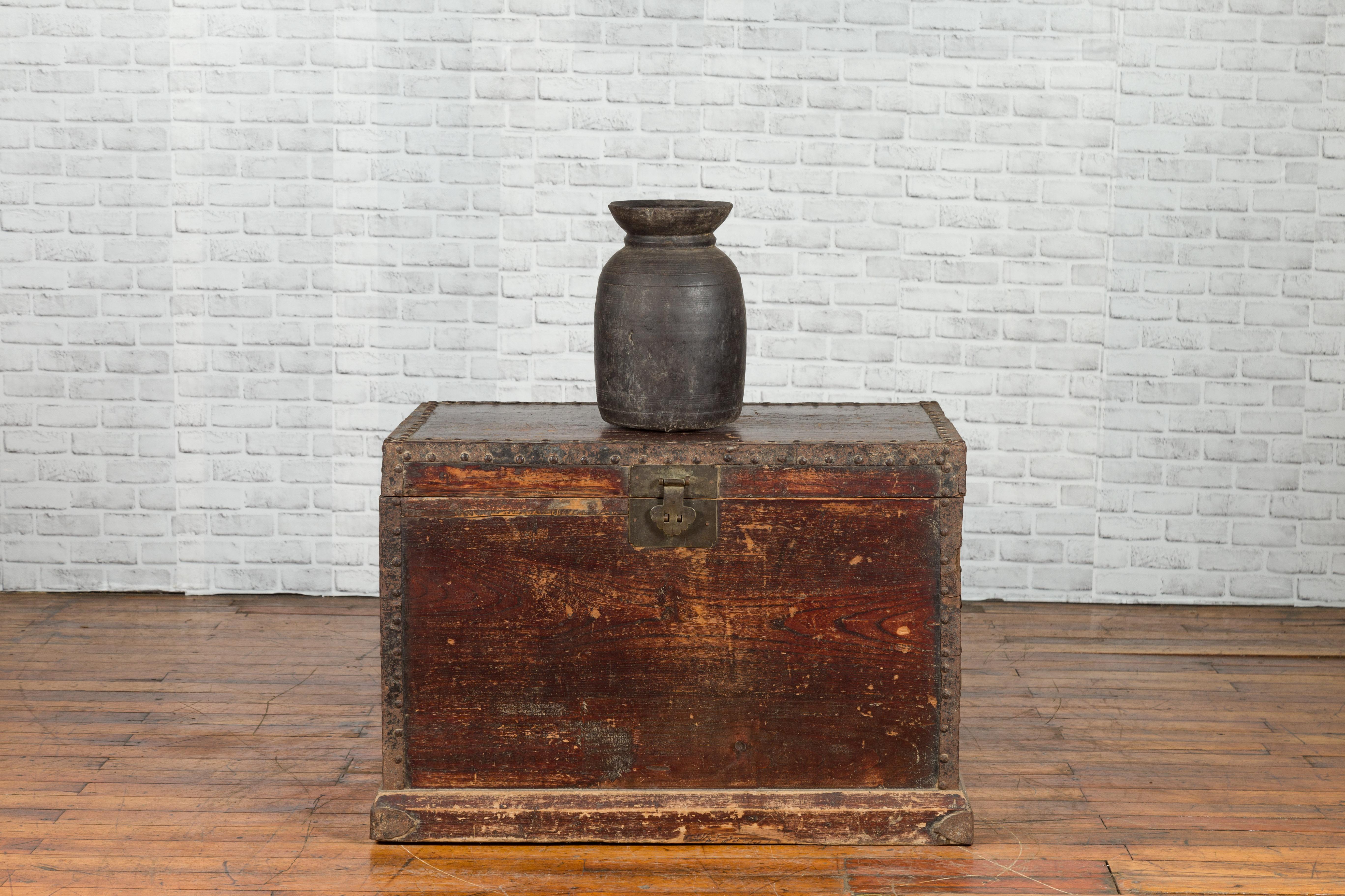 A large Chinese Qing Dynasty period distressed blanket chest from the 19th century, with iron fittings and lateral handles. Created in China during the Qing dynasty, this chest features a linear silhouette rhythmically accented with iron studs and