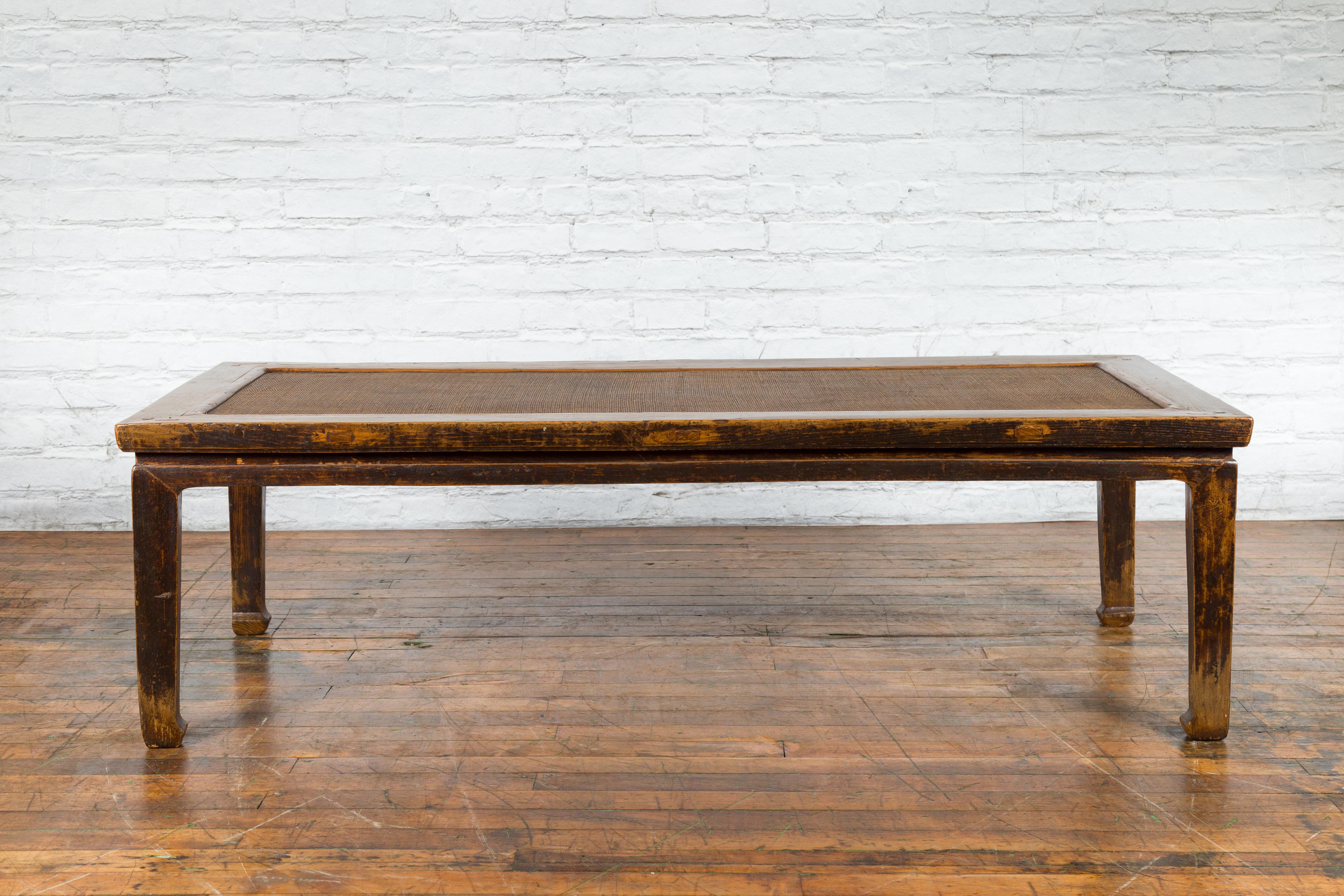 A large Chinese Qing Dynasty period elmwood coffee table from the 19th century, with rattan top and straight horse hoof legs. Created in China during the Qing Dynasty in the 19th century, this large elmwood coffee table features a rectangular top