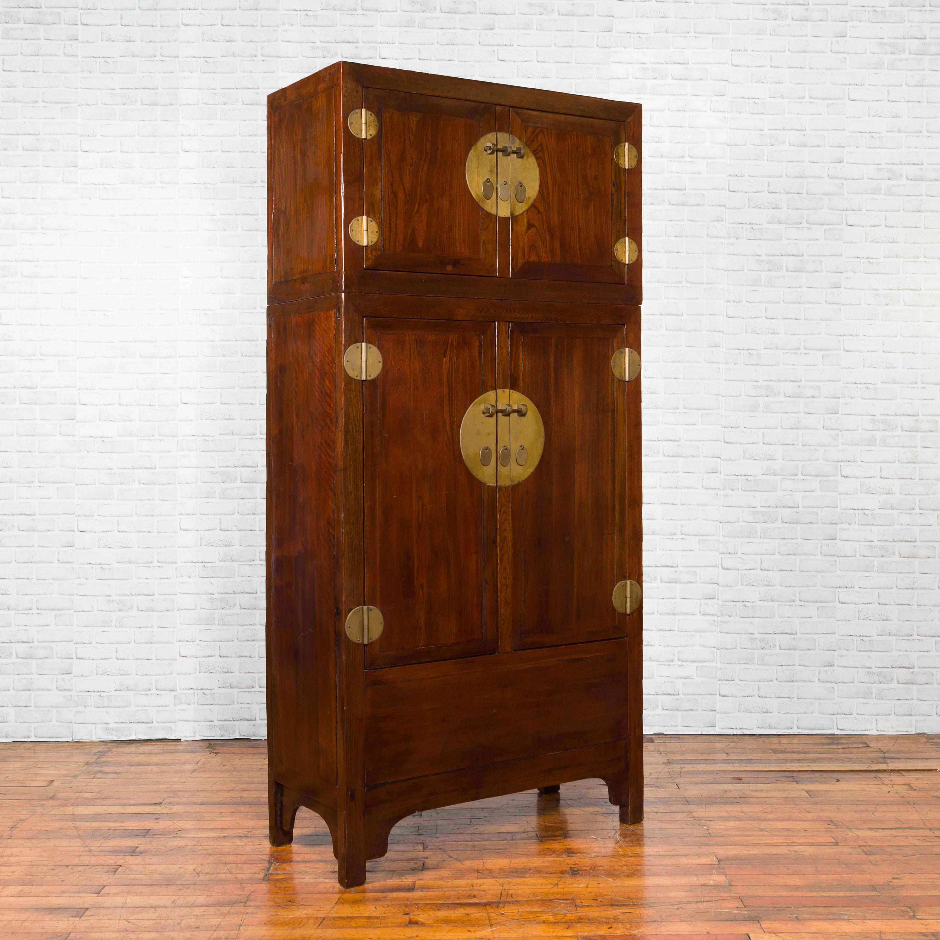 A Chinese Qing Dynasty period elm and burl wood compound multiseason cabinet from the 19th century, with four doors, inner shelves and hidden drawers. Created in China during the 19th century, this tall two-section compound cabinet features a linear
