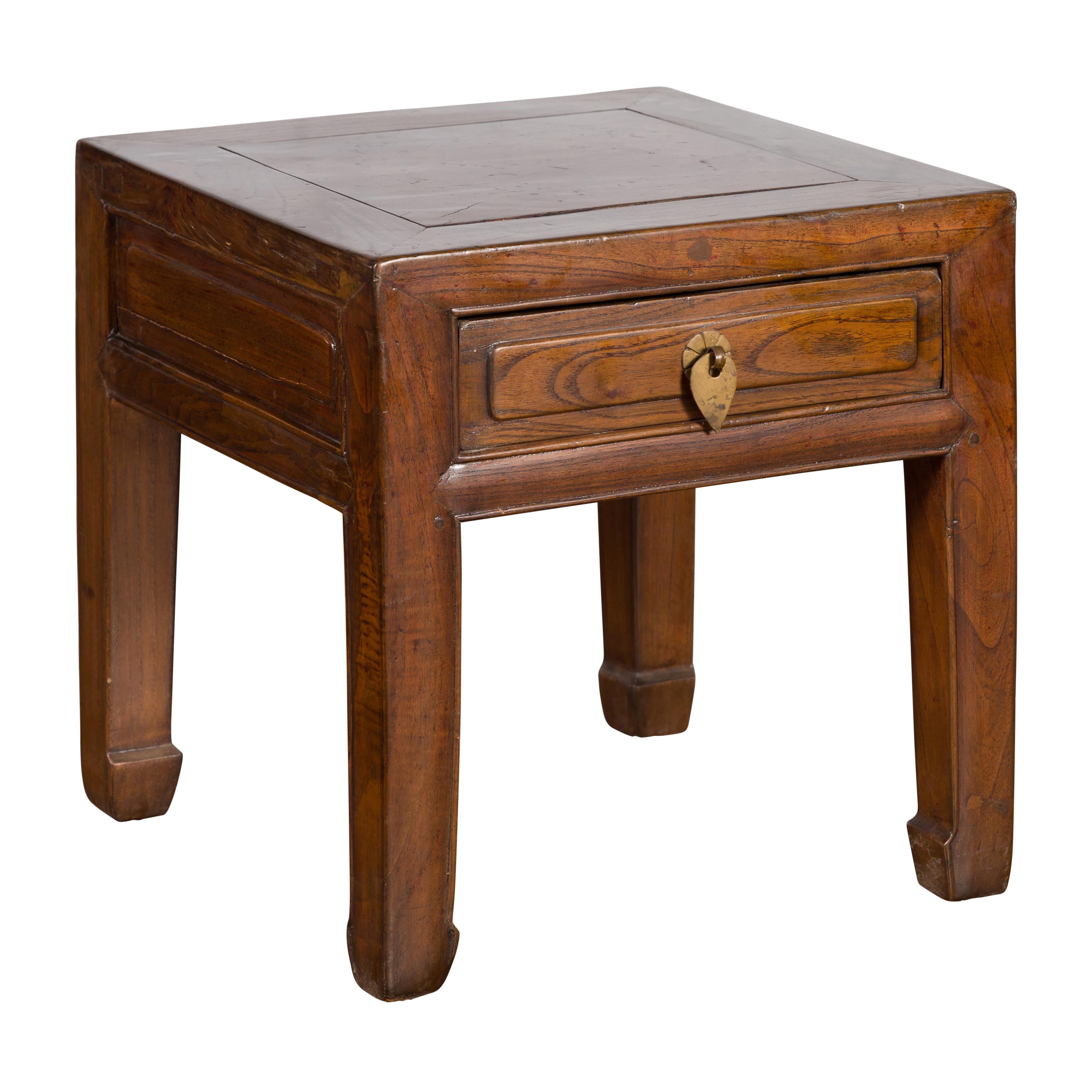 A Chinese Qing Dynasty period elmwood side table from the 19th century, with single drawer, brass hardware and horse hoof feet. Created in China during the Qing Dynasty period, this elm side table features a square top sitting above a single drawer