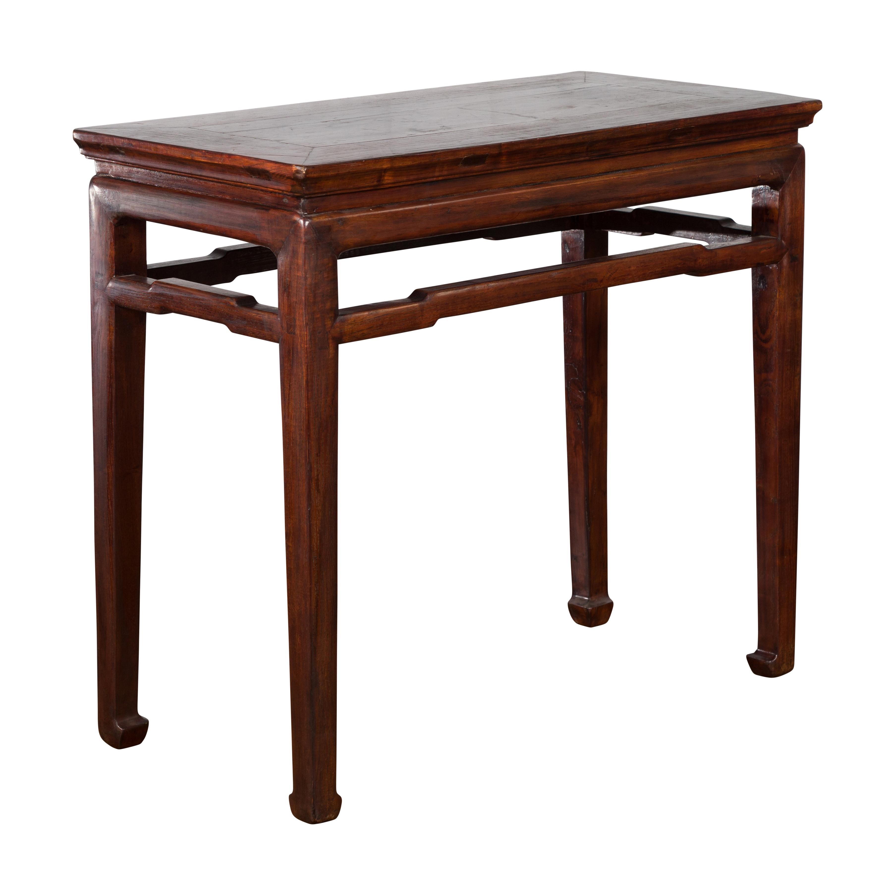 A Chinese Qing Dynasty period Elmwood wine tasting console table from the 19th century, with humpback stretcher and horse hoof feet. Created in China during the Qing Dynasty, this Elmwood wine table features a rectangular top with central board,